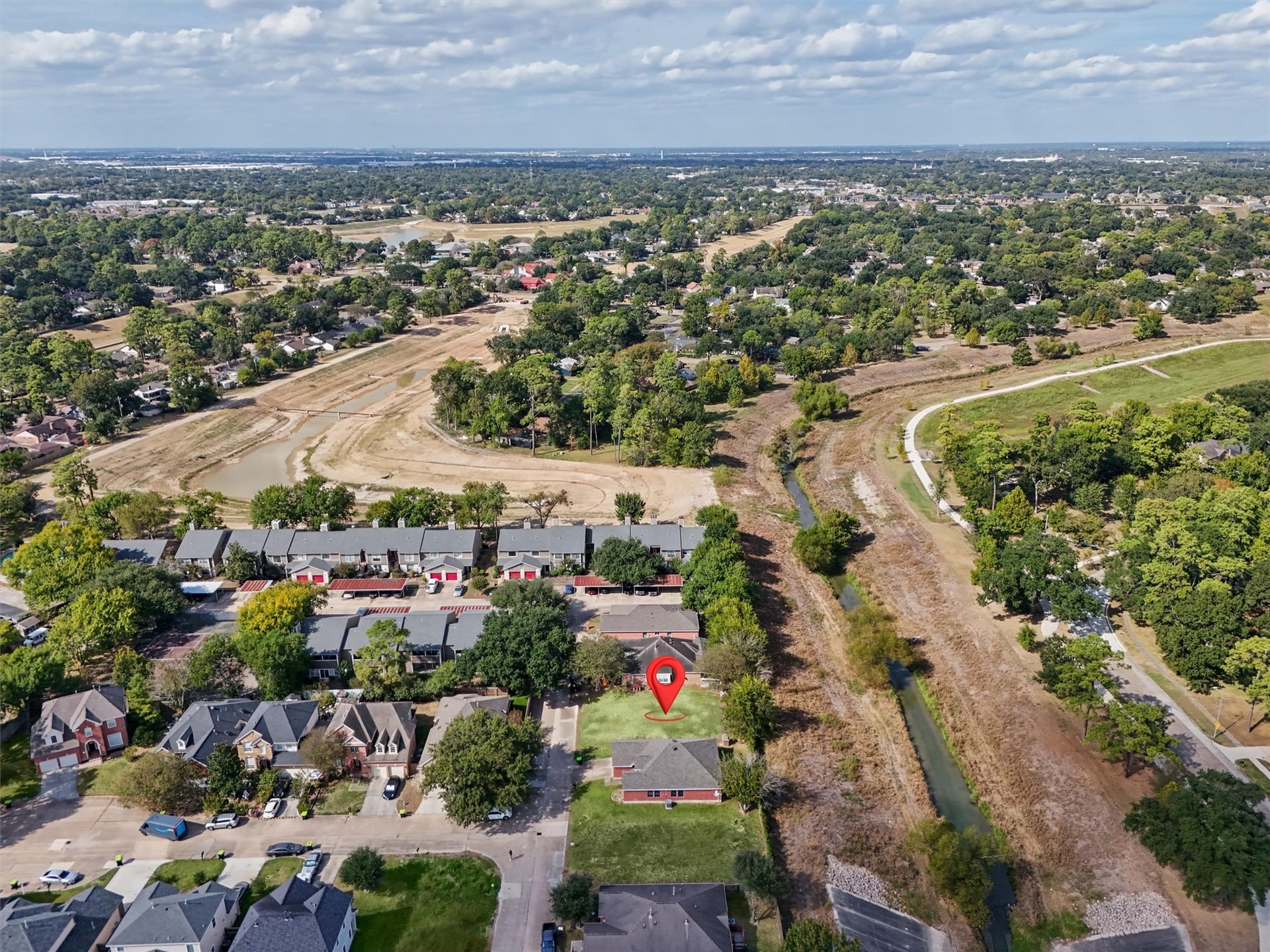4444 Victory Dr, Houston, TX 77088 The red arrow highlights this cleared residential lot, surrounded by established homes, mature trees, and beautiful green spaces. This aerial view showcases the nearby walking trails, winding waterway, and expansive open areas that add to the neighborhood's charm. Enjoy the convenience of nearby shopping, dining, and everyday amenities while creating your own custom dream home in this inviting residential setting.