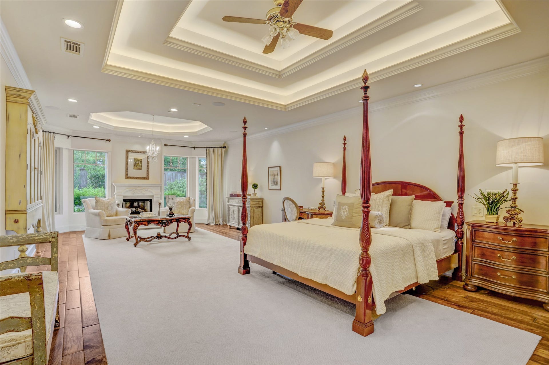 The spacious primary suite with raised ceilings and a stone mantle over the gas log fireplace