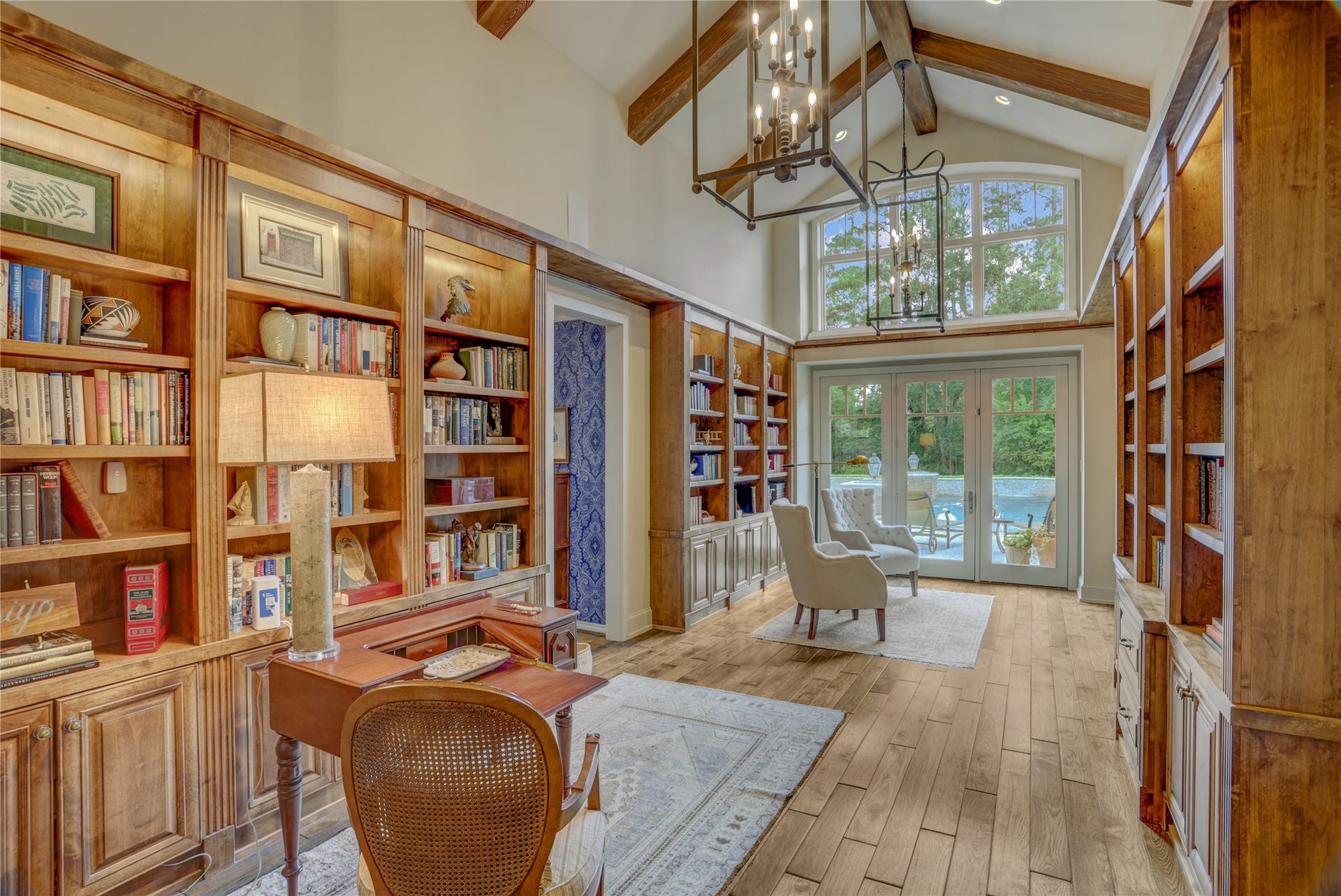 The dramatic study with custom light fixtures, vaulted ceiling, bookcases and a world class view of the patios, pool and pavilion