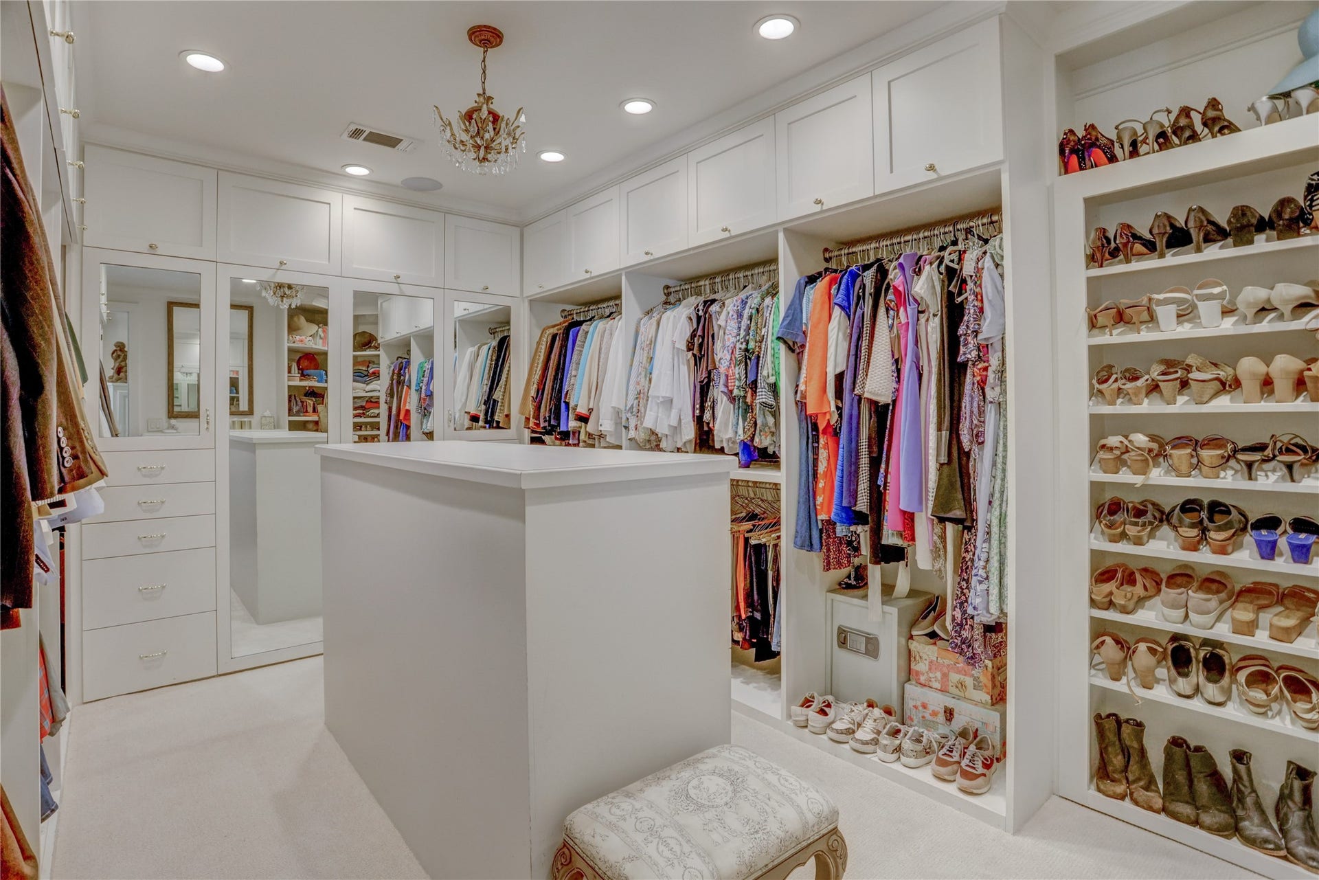 The primary closet has plenty of hanging space, built ins, shoe racks, a packing island with additional drawers as well as more hanging space