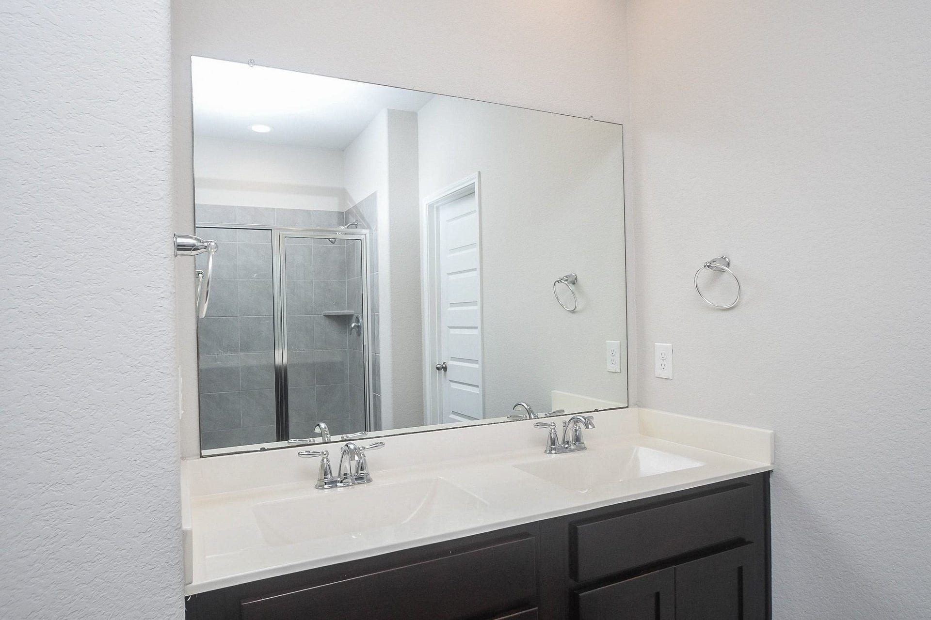 Elegant primary bathroom with a spacious double vanity, sleek fixtures, and a large mirror.