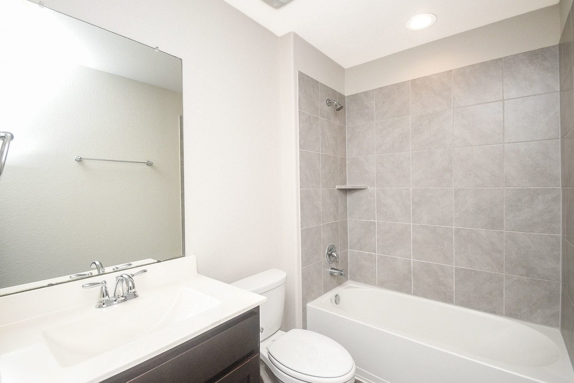 Modern full bathroom upstairs featuring a sleek vanity, large mirror, and a spacious tub with elegant tile surround.