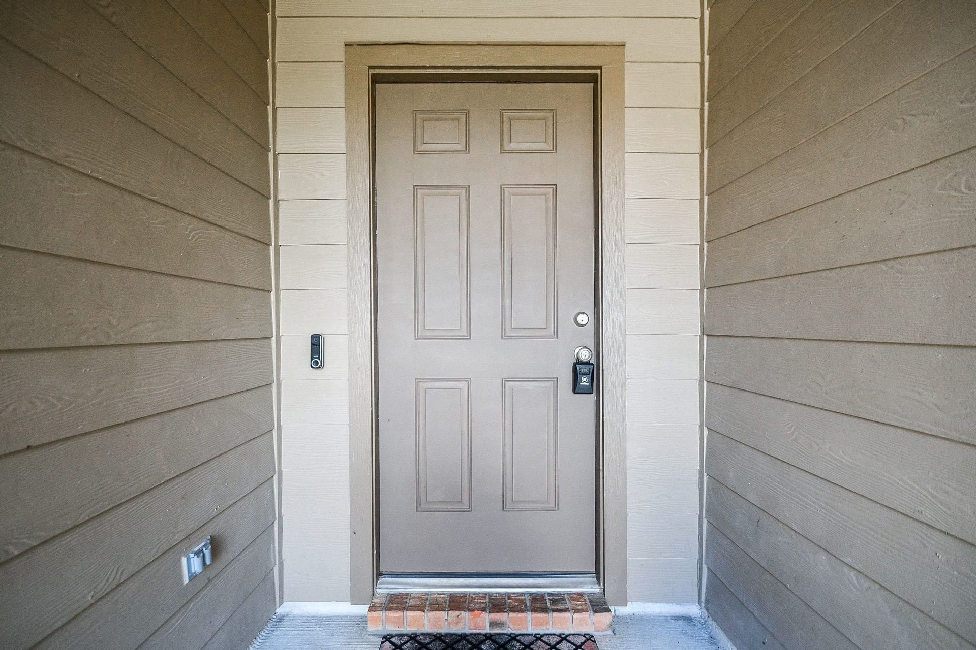 Inviting entryway with a sturdy door, accented by clean, modern siding and a welcoming porch light.