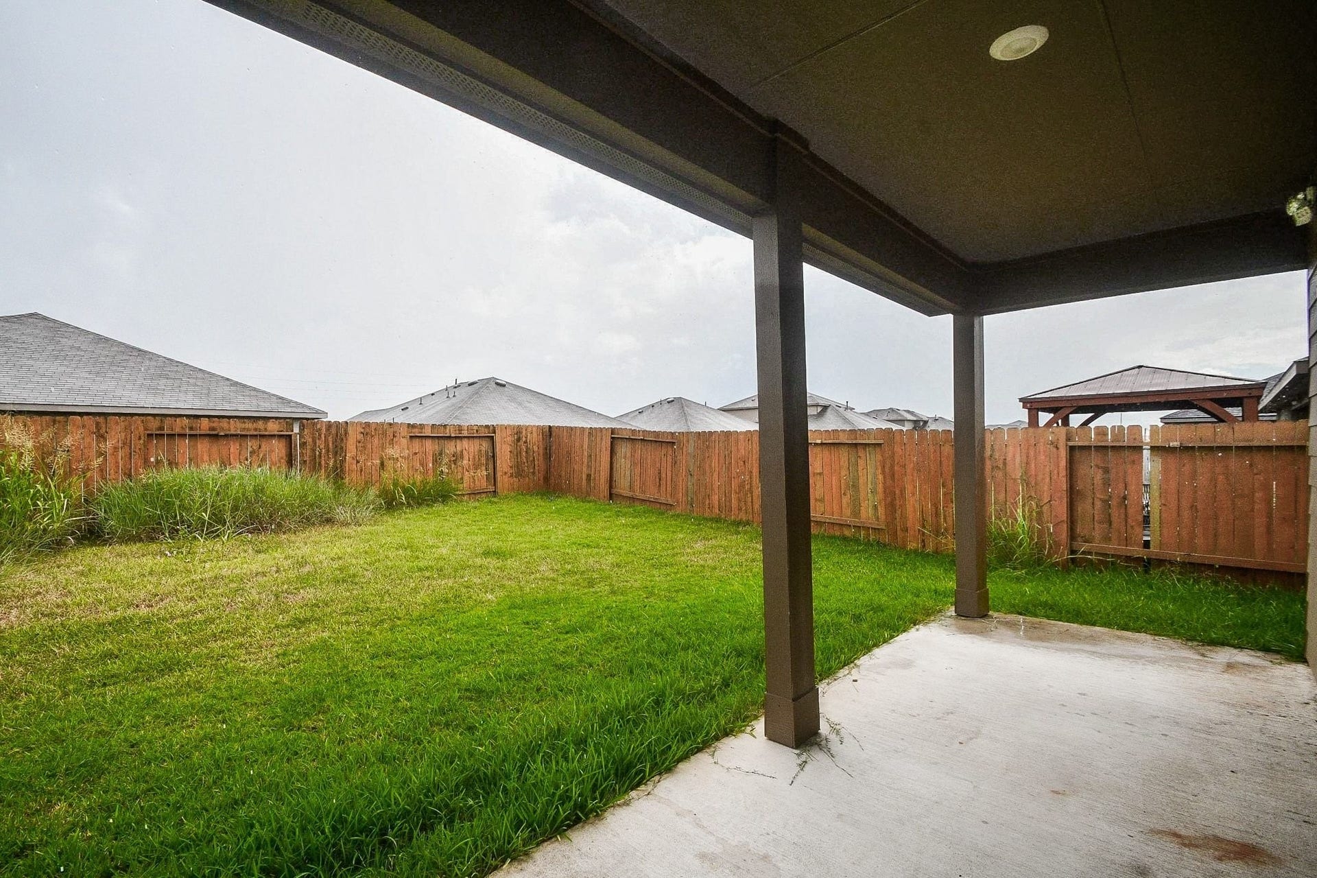 Step into a spacious backyard featuring a covered patio and a wooden fence, perfect for outdoor relaxation and privacy.