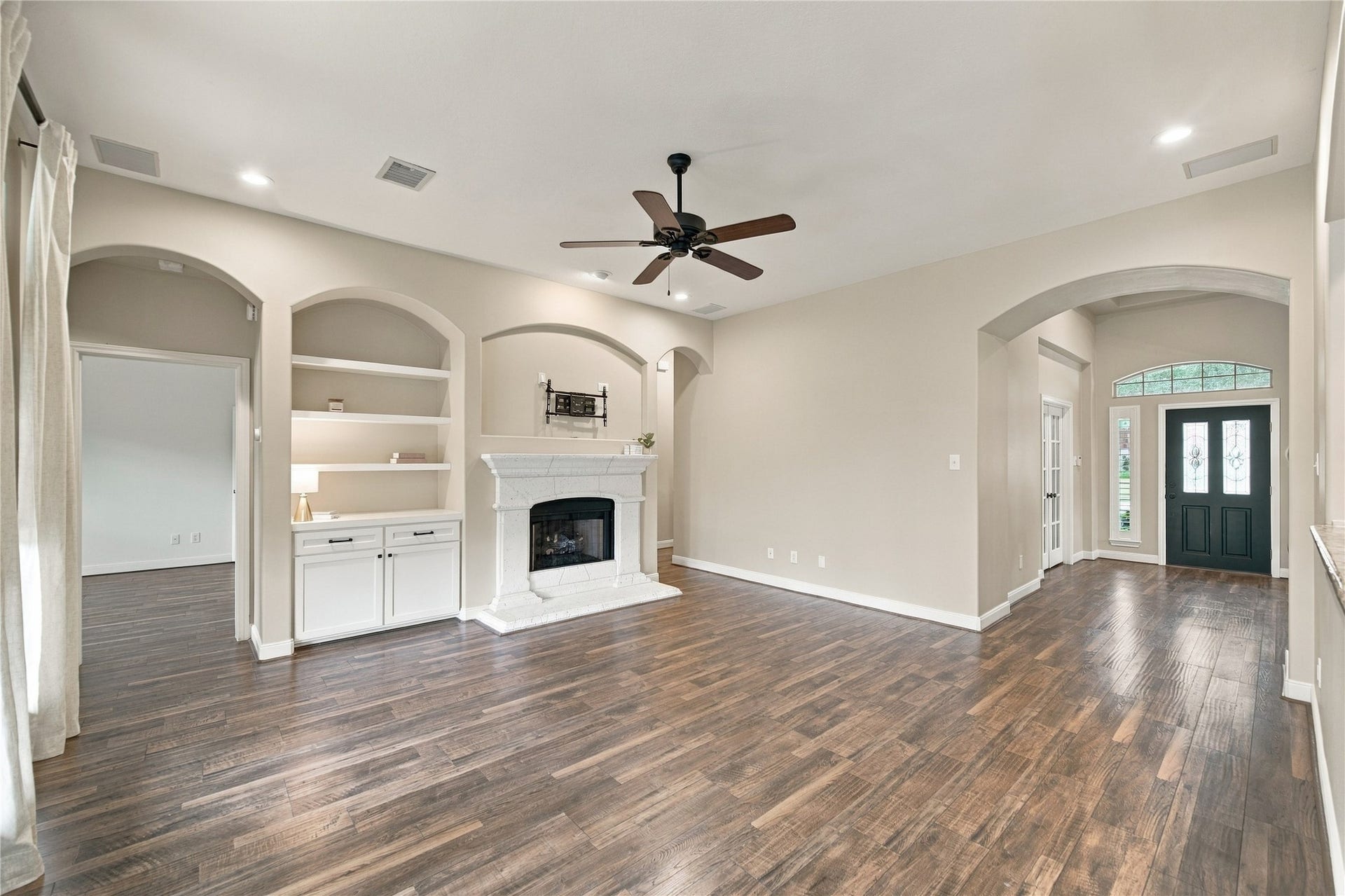 23706 Indian Hills Way, Katy, TX 77494 From this view of the family room, you'll see the doorway to the primary bedroom suite on the left, offering convenient access and separation from the secondary bedrooms. Notice the beautiful arched openings, built-in shelving, and cozy gas fireplace!