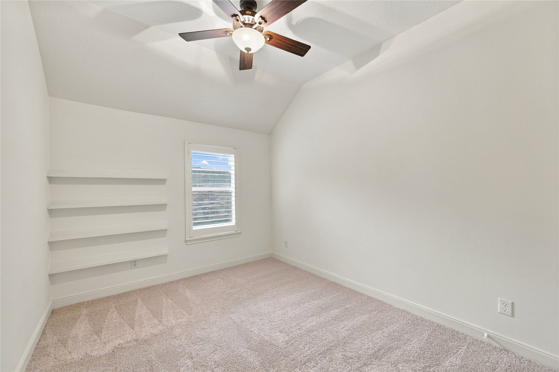 23706 Indian Hills Way, Katy, TX 77494 This charming secondary bedroom features a vaulted ceiling, plantation shutters, new carpet, and built-in book rails, perfect for displaying favorite books and keeping them within easy reach.