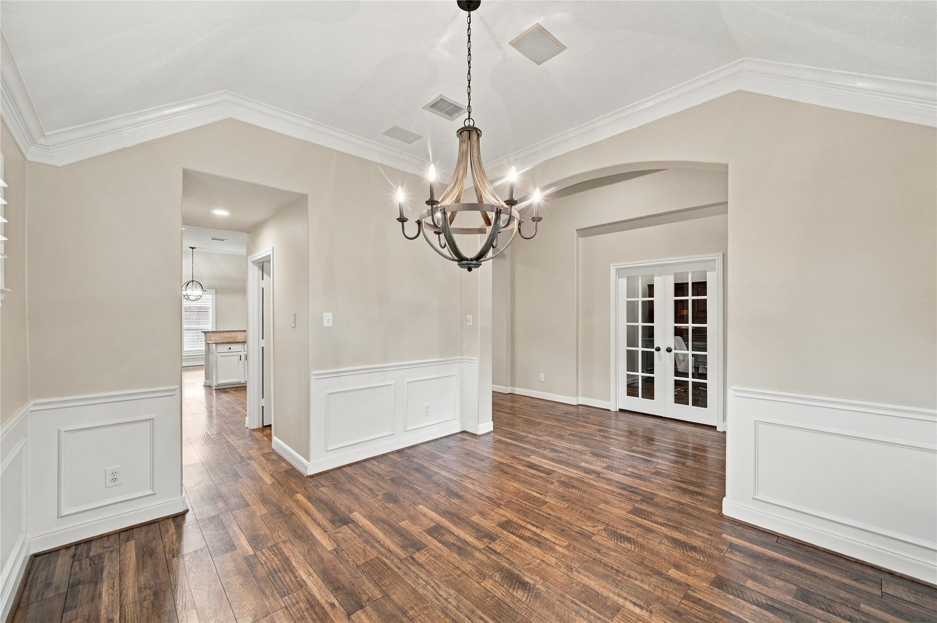 23706 Indian Hills Way, Katy, TX 77494 From this angle of the dining room, you can appreciate the home's thoughtfully planned architectural details, including elegant arched openings, beautiful crown molding, and decorative wall paneling. The rich wood-look flooring adds warmth and character.