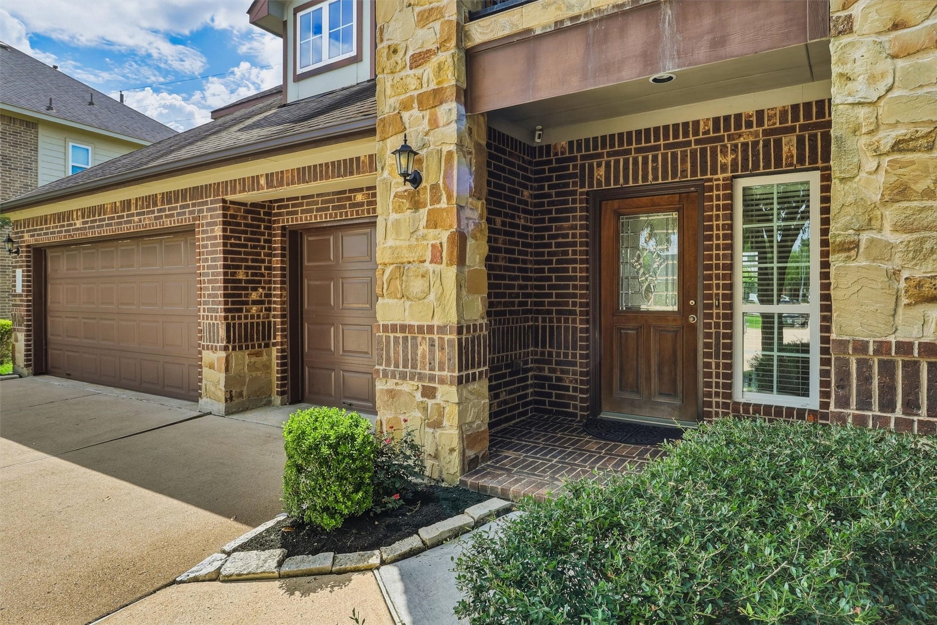 3219 Cotton Ranch Drive, Katy, TX 77494 A charming covered front porch sets the stage for a warm welcome, while the timeless brick and stone elevation, elegant decorative glass front door, and professionally landscaped grounds create unforgettable curb appeal.