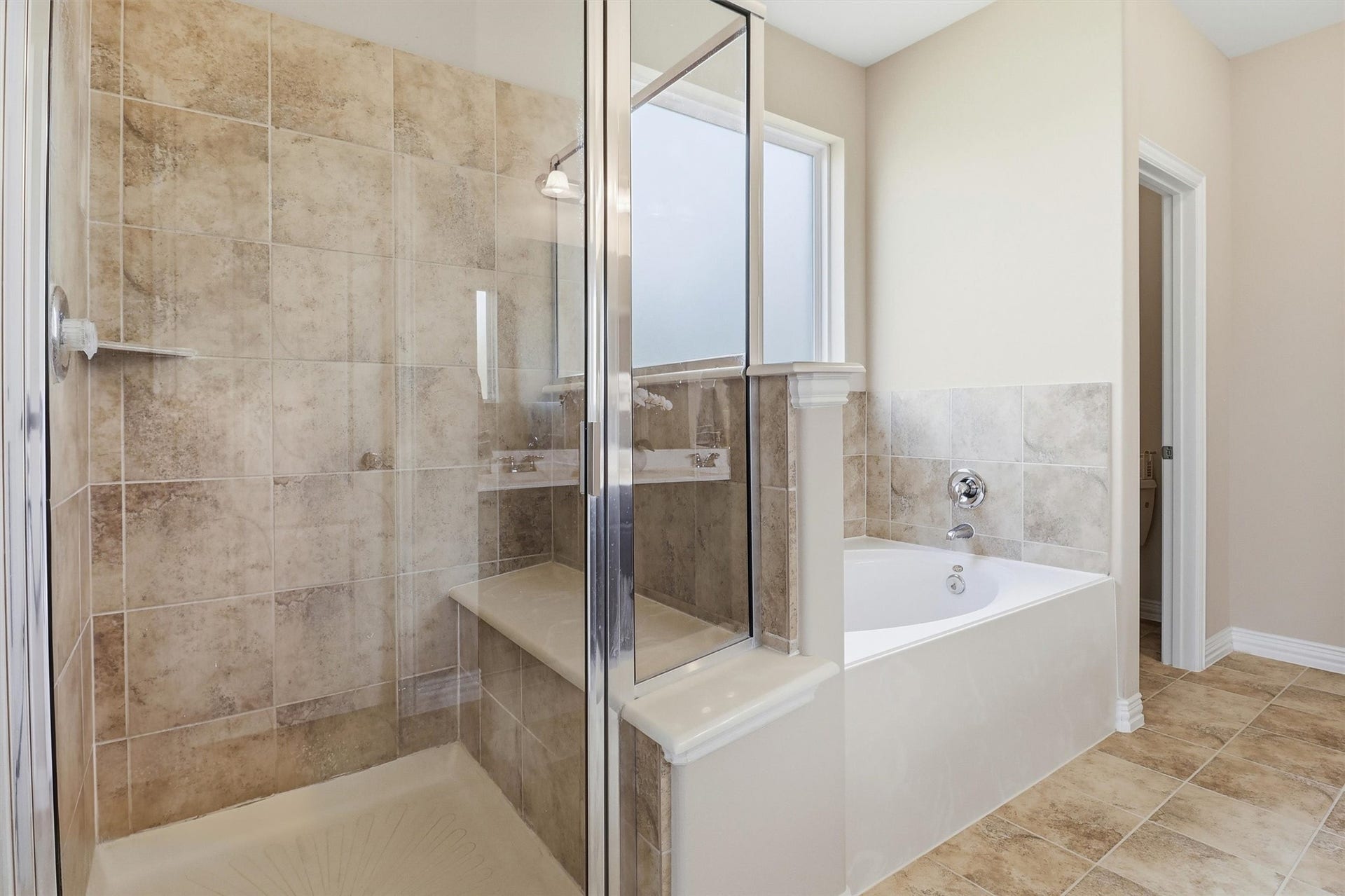 3219 Cotton Ranch Drive, Katy, TX 77494 Relax in the oversized soaking tub beneath a large privacy window or refresh in the spacious glass-enclosed shower featuring an elegant tile surround and built-in bench.