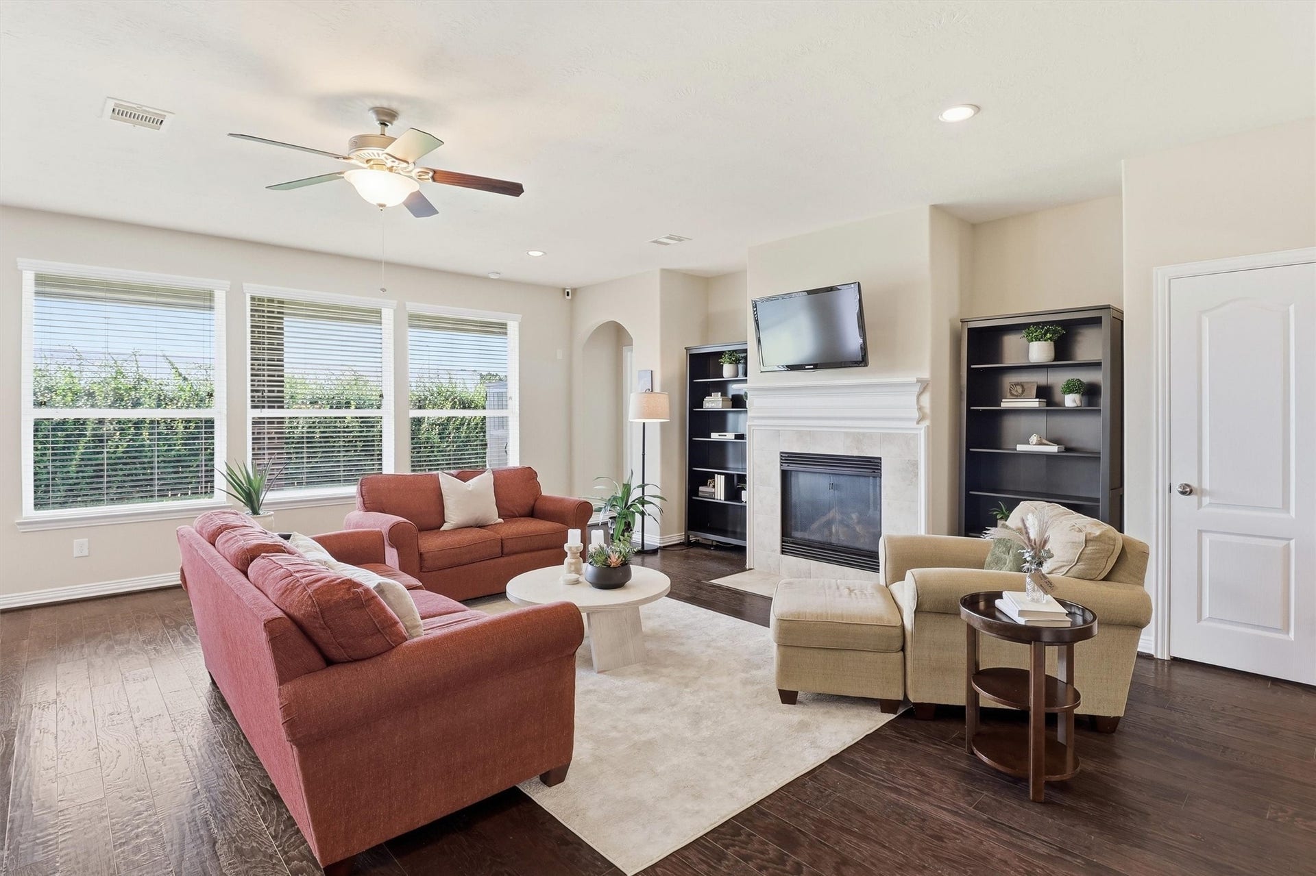 3219 Cotton Ranch Drive, Katy, TX 77494 Rich wood flooring, recessed lighting, and a ceiling fan complement the spacious layout, while oversized windows spanning the back wall flood the room with natural light and showcase peaceful views of the backyard.