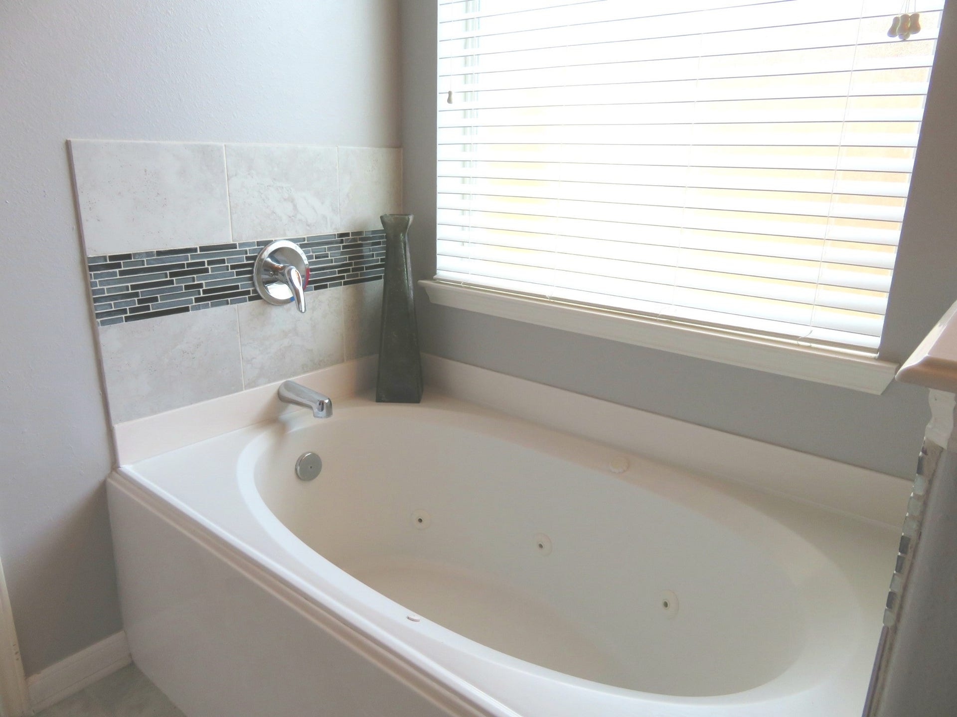 4530 Hall Croft Chase Lane, Katy, TX 77449 Relax in the elegant bathroom featuring a luxurious jetted tub, complemented by modern tile accents and abundant natural light.