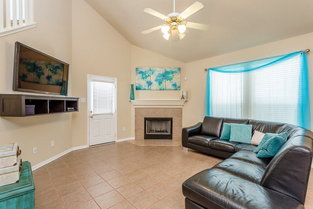 4530 Hall Croft Chase Lane, Katy, TX 77449 Cozy fireplace, and large sectional sofa, complemented by abundant natural light and elegant tile flooring.