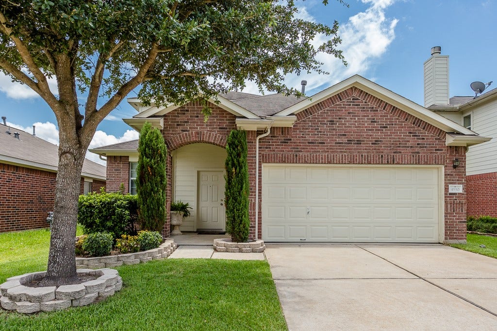 4530 Hall Croft Chase Lane, Katy, TX 77449 Charming brick home with a welcoming arched entryway, neatly landscaped front yard, and a spacious two-car garage.