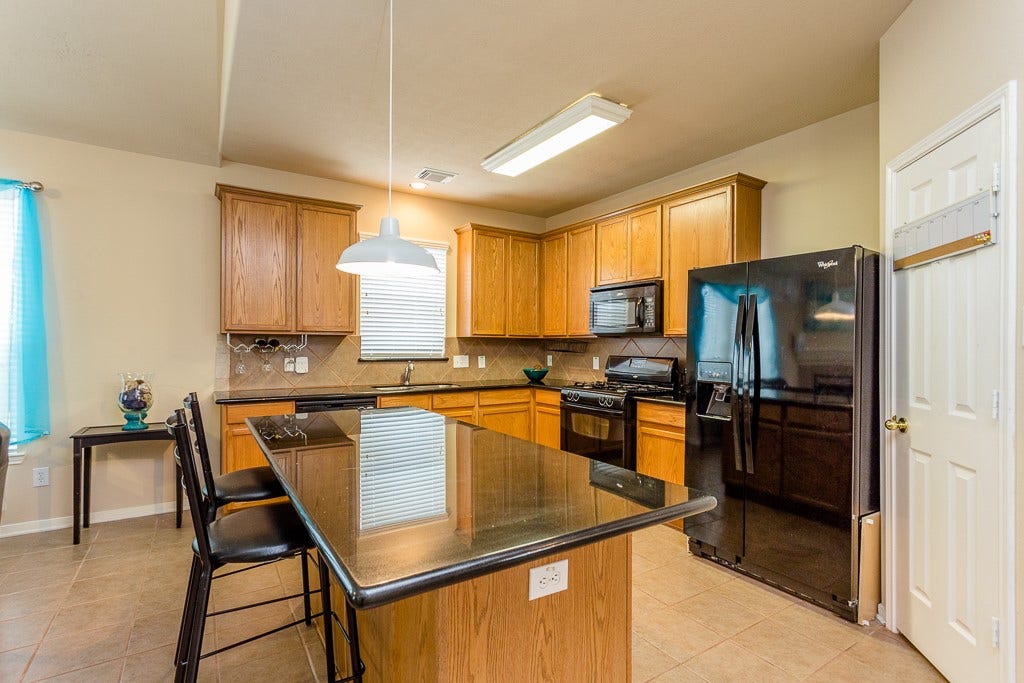 4530 Hall Croft Chase Lane, Katy, TX 77449 Spacious kitchen featuring sleek black appliances, a large island with seating, and ample wood cabinetry for storage.