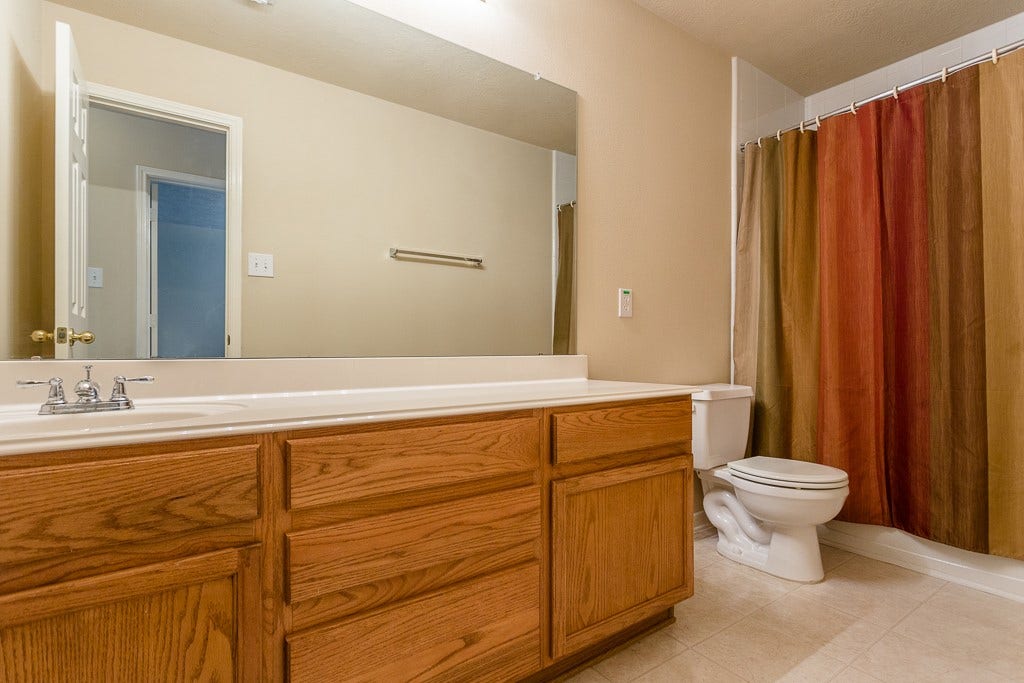 4530 Hall Croft Chase Lane, Katy, TX 77449 Upstairs bathroom featuring a large mirror, elegant wood cabinetry.