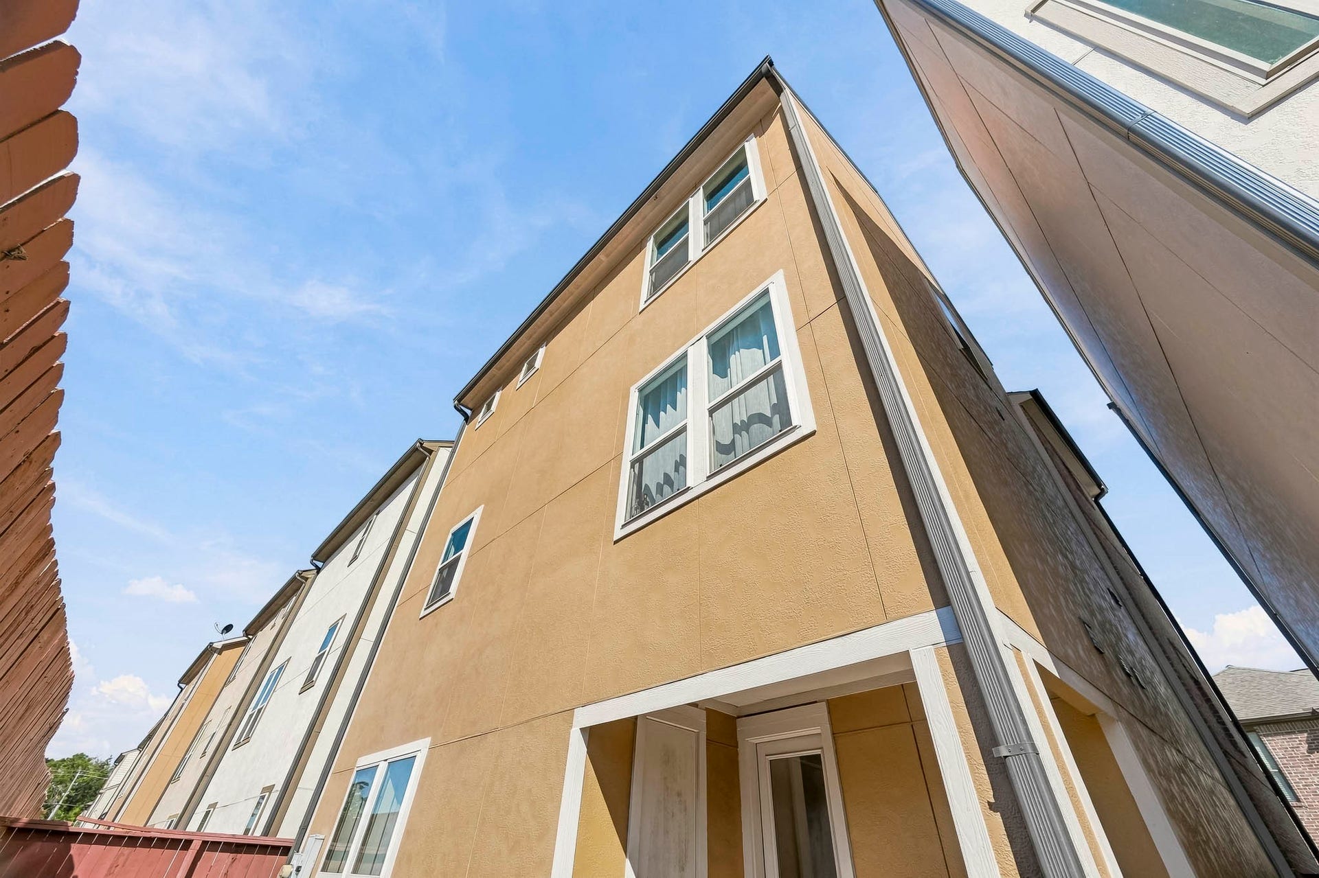 11009 Upland Forest Drive, Houston, TX 77043 Modern three-story townhouse with a sleek exterior, featuring large windows and a private entrance, nestled in a cozy urban setting.