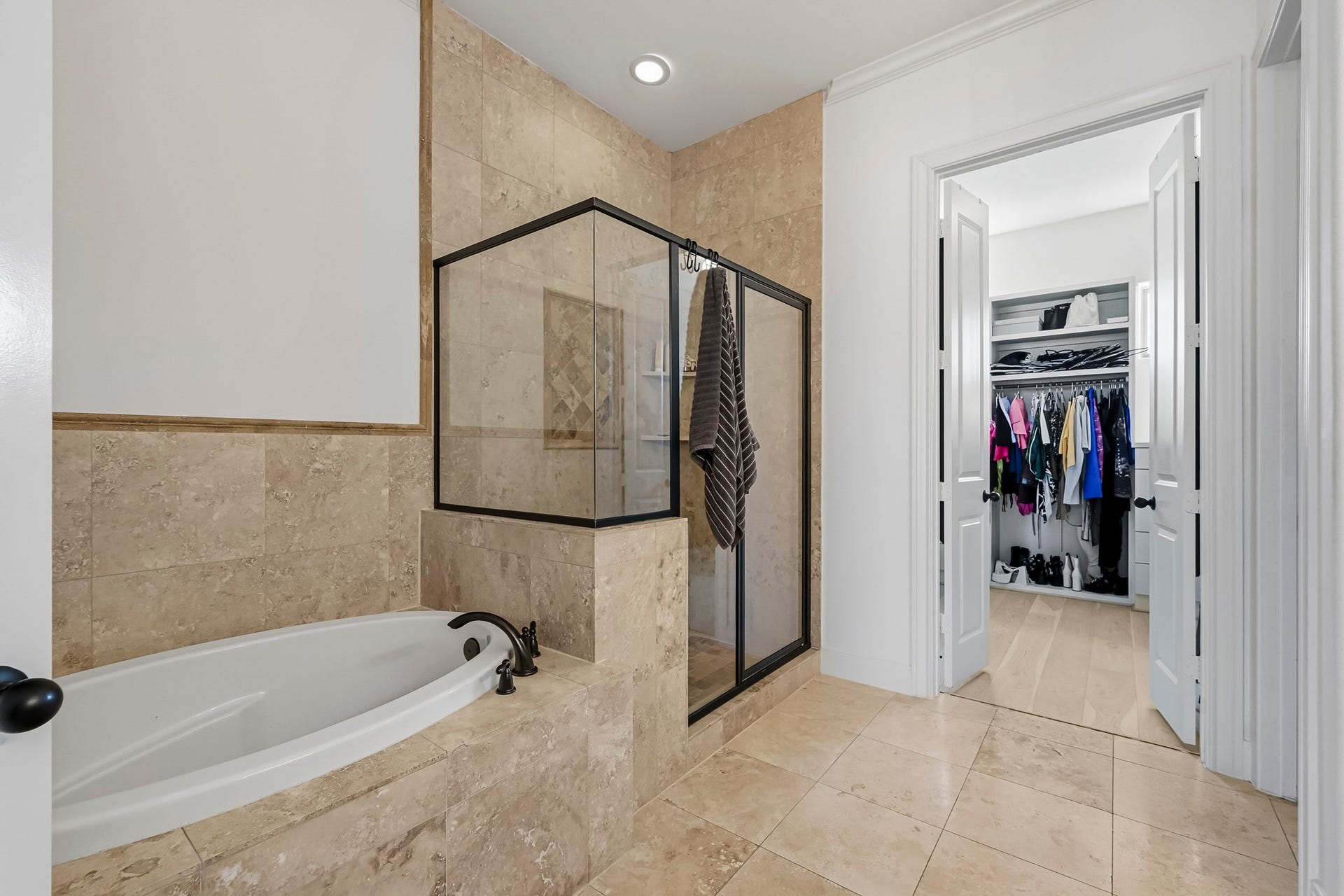 11009 Upland Forest Drive, Houston, TX 77043 Luxurious bathroom featuring a spacious soaking tub and a sleek glass-enclosed shower, seamlessly connected to a generous walk-in closet with ample storage space.