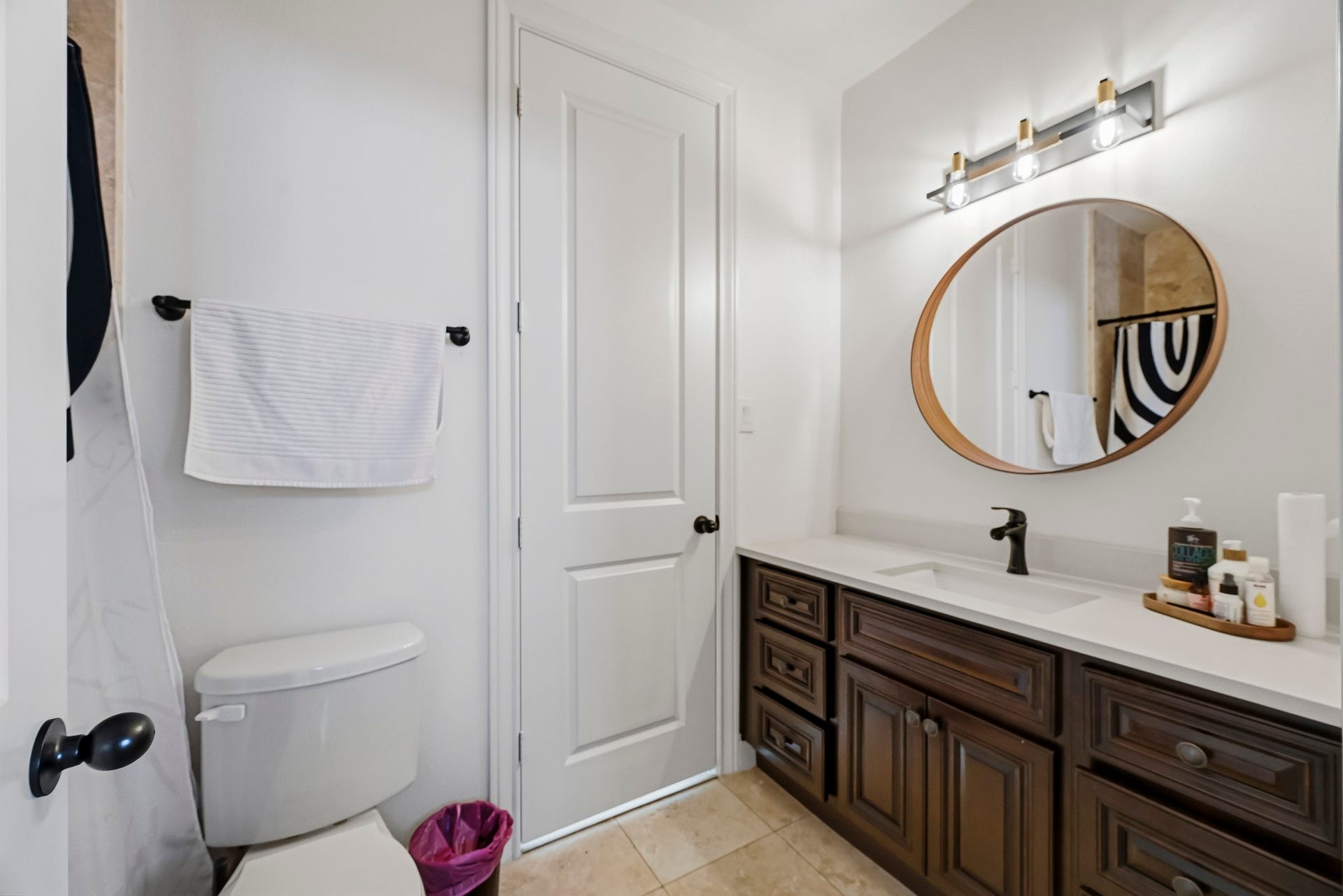 11009 Upland Forest Drive, Houston, TX 77043 Elegant bathroom featuring a stylish vanity with a round mirror, modern lighting, and ample storage space.