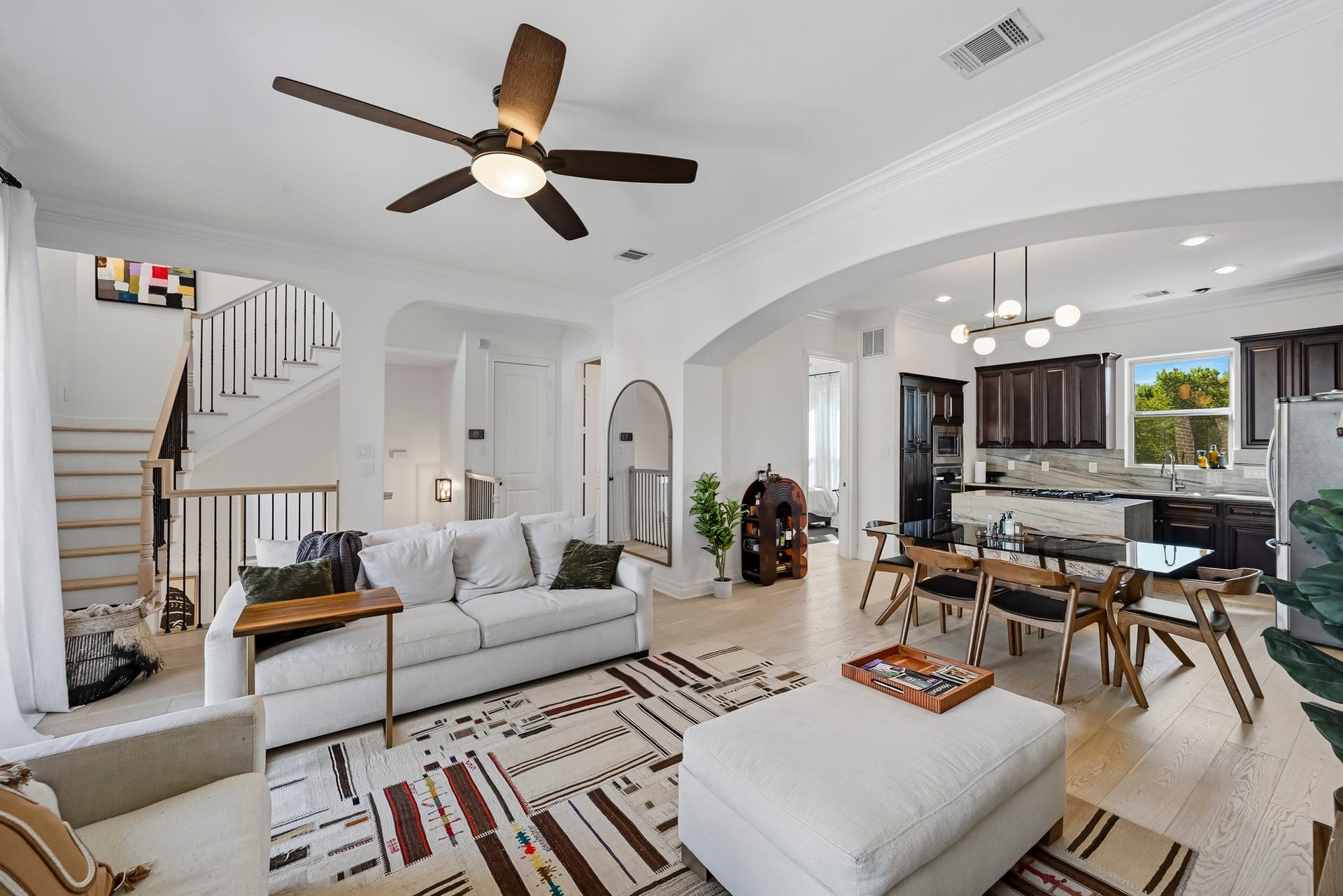 11009 Upland Forest Drive, Houston, TX 77043 Bright and open living space featuring comfortable seating, stylish area rug, and a seamless flow into the dining area and kitchen with dark cabinetry and stainless steel appliances.