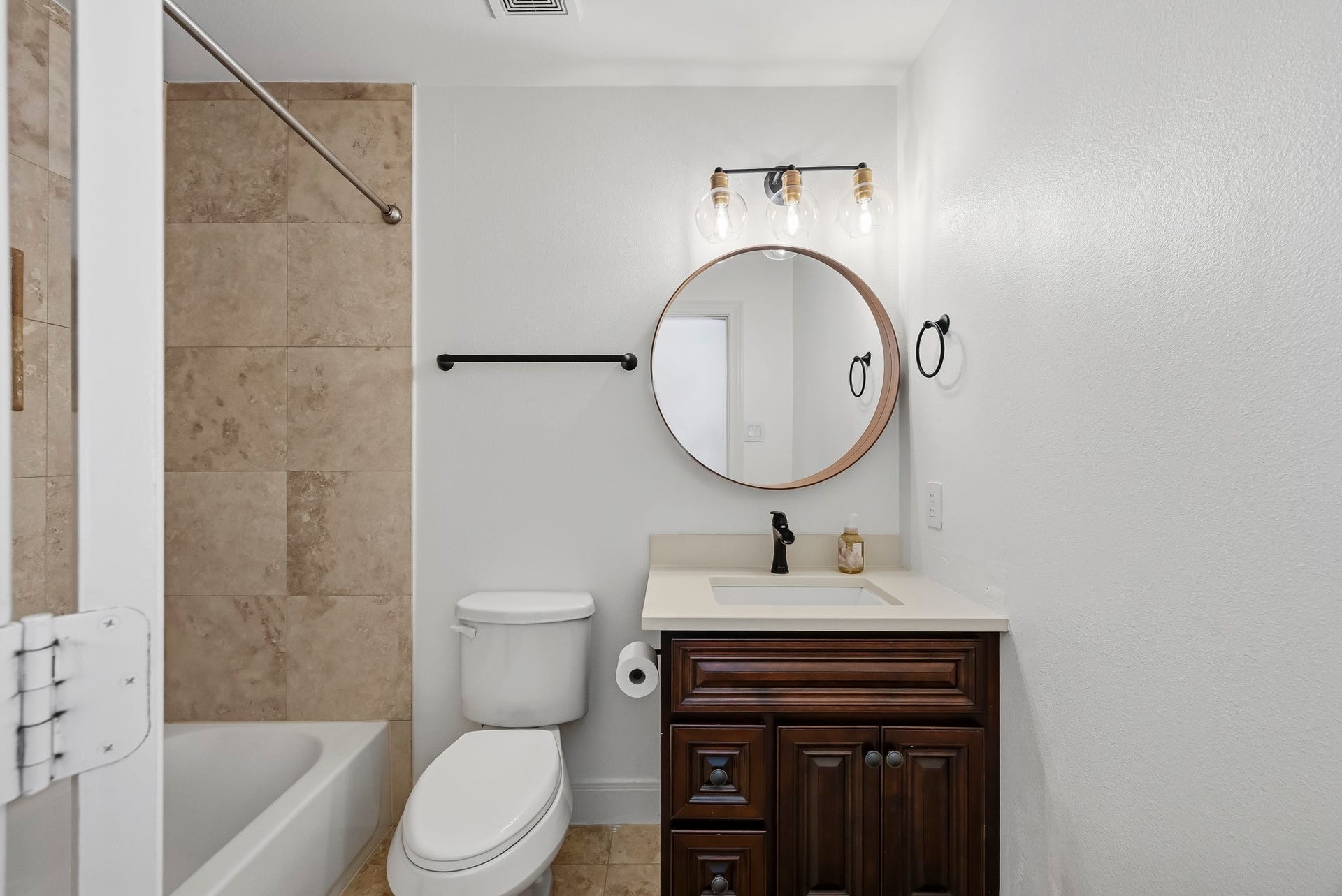 11009 Upland Forest Drive, Houston, TX 77043 Charming bathroom featuring a modern vanity with a round mirror and elegant lighting, complemented by a tiled shower and neutral tones.