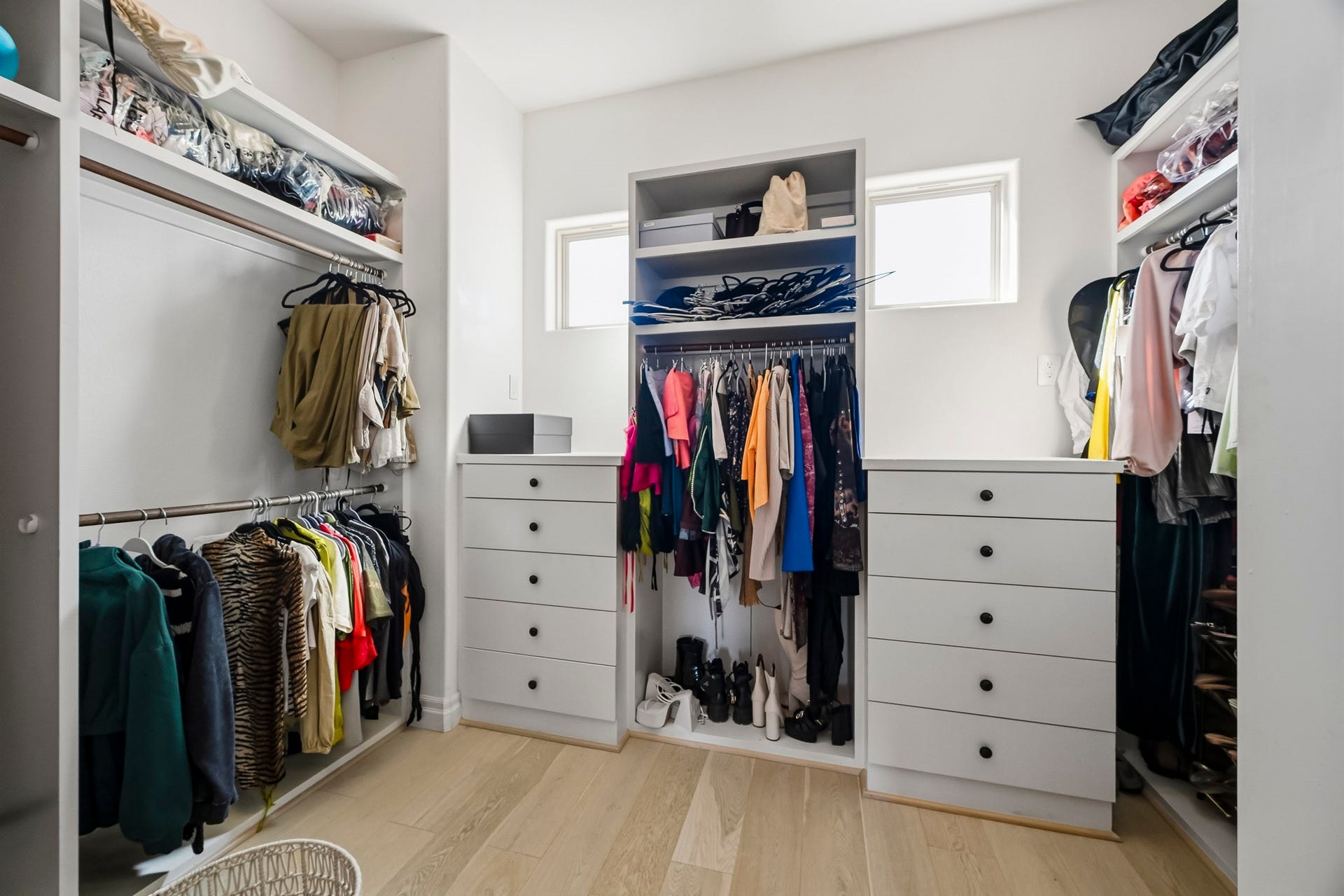 11009 Upland Forest Drive, Houston, TX 77043 Spacious walk-in closet with ample storage, featuring built-in shelves, drawers, and hanging space, accented by natural light from two small windows.