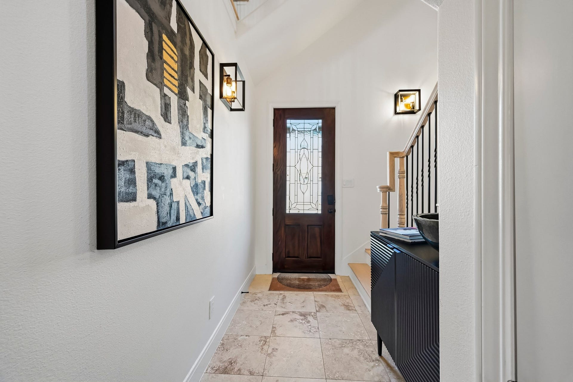 11009 Upland Forest Drive, Houston, TX 77043 Inviting entryway featuring a stylish wooden door with decorative glass, elegant tile flooring, and modern wall sconces.