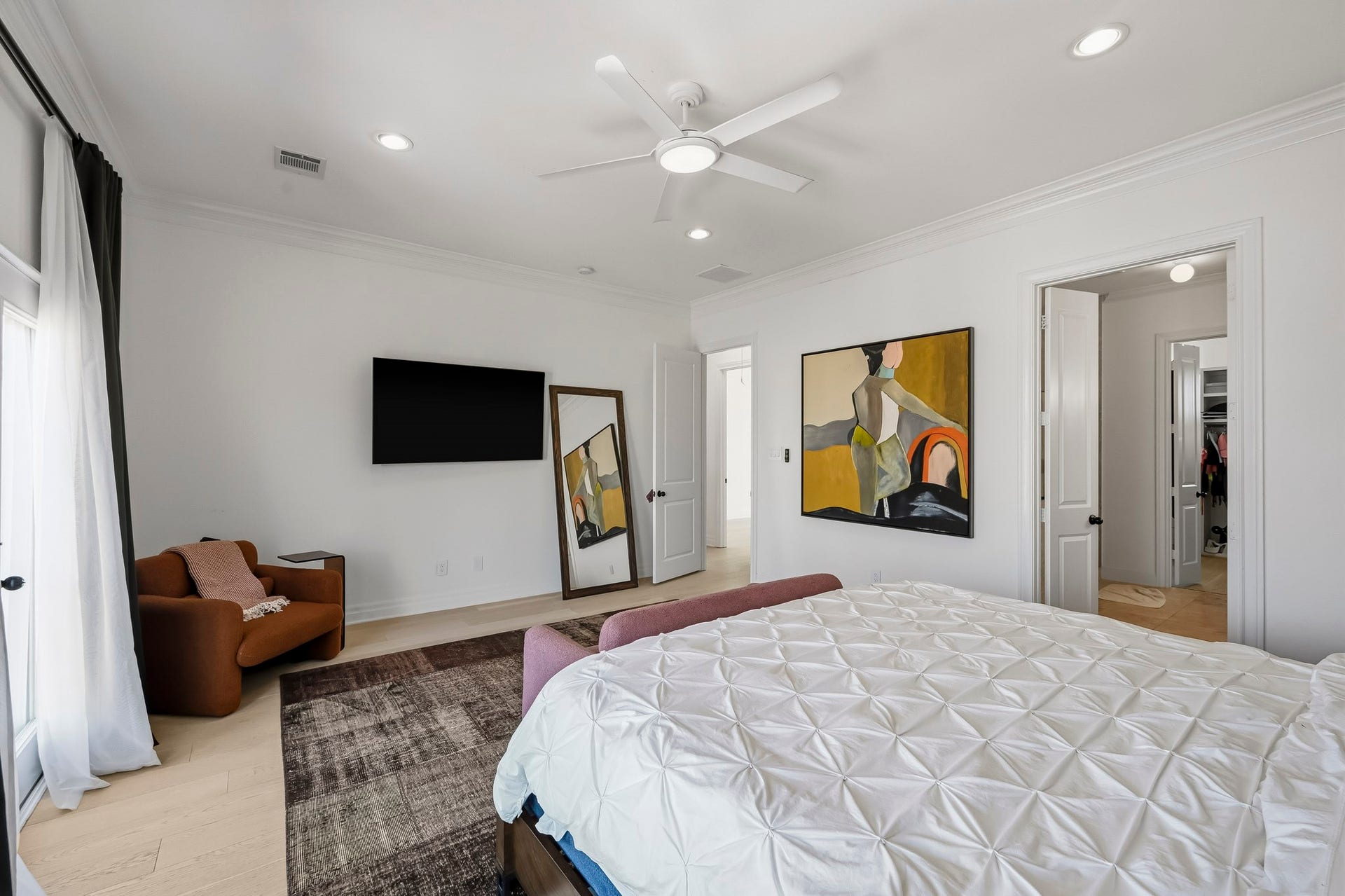 11009 Upland Forest Drive, Houston, TX 77043 Spacious bedroom featuring modern decor, a cozy seating area, and a wall-mounted TV, with ample natural light and an attached bathroom.