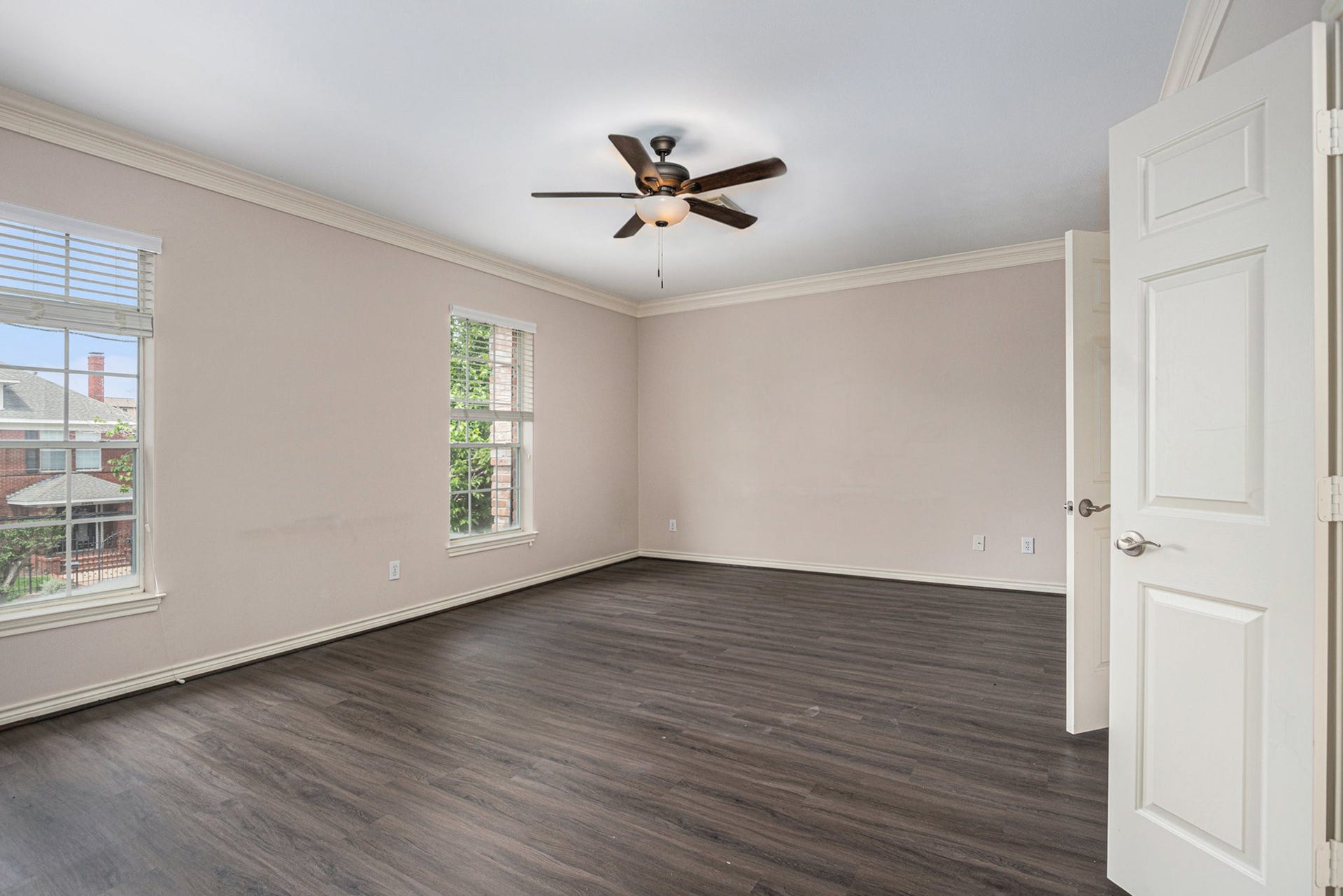5001 Jackson Street, Houston, TX 77004 Spacious, bright room with large windows, neutral walls, and dark wood flooring. Features a ceiling fan and ample natural light, ideal for a bedroom or office.