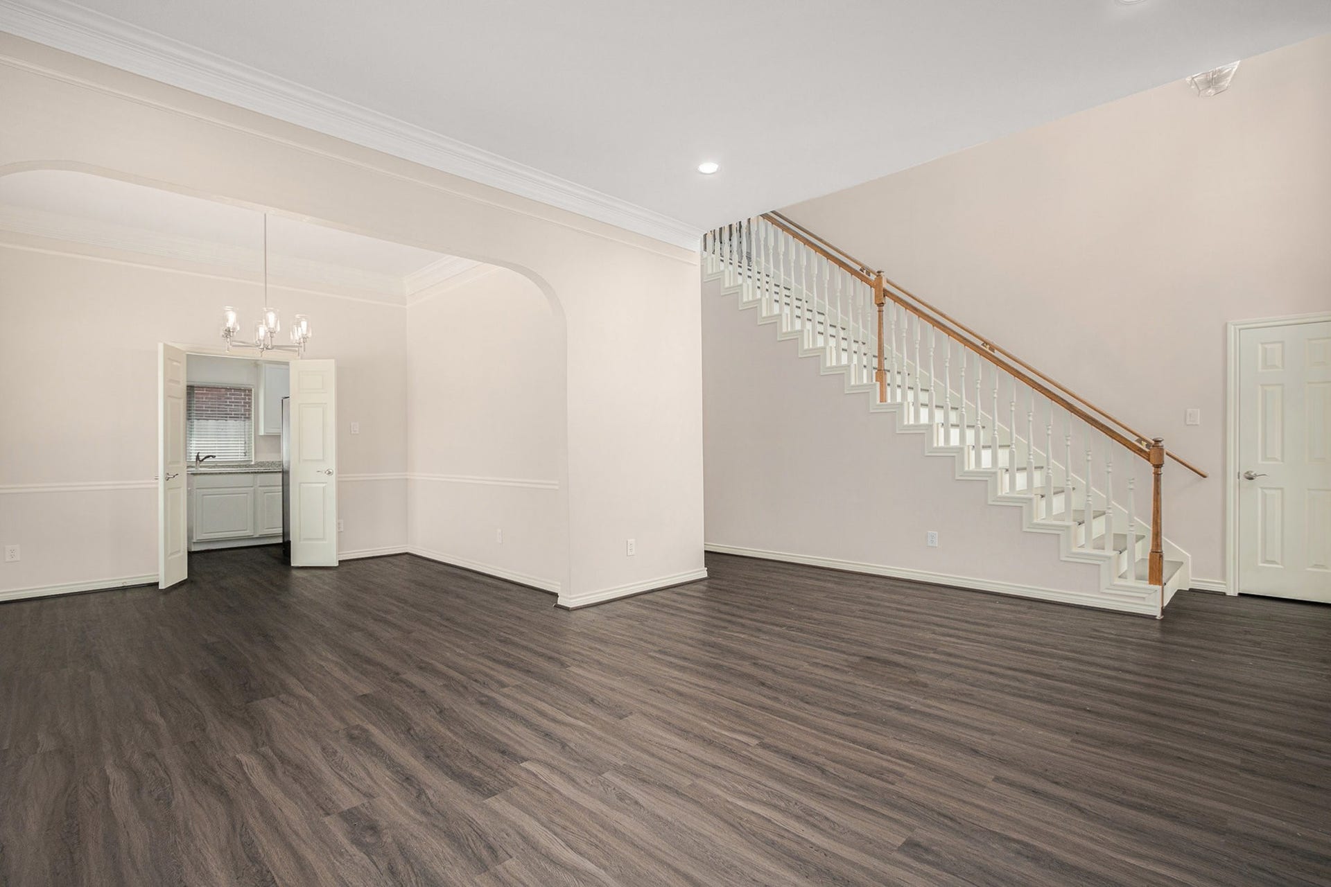 5001 Jackson Street, Houston, TX 77004 This spacious, light-filled living area features elegant dark wood flooring, a charming chandelier, and a classic staircase. It opens to a dining area with double doors leading to the kitchen, offering a seamless flow for entertaining.