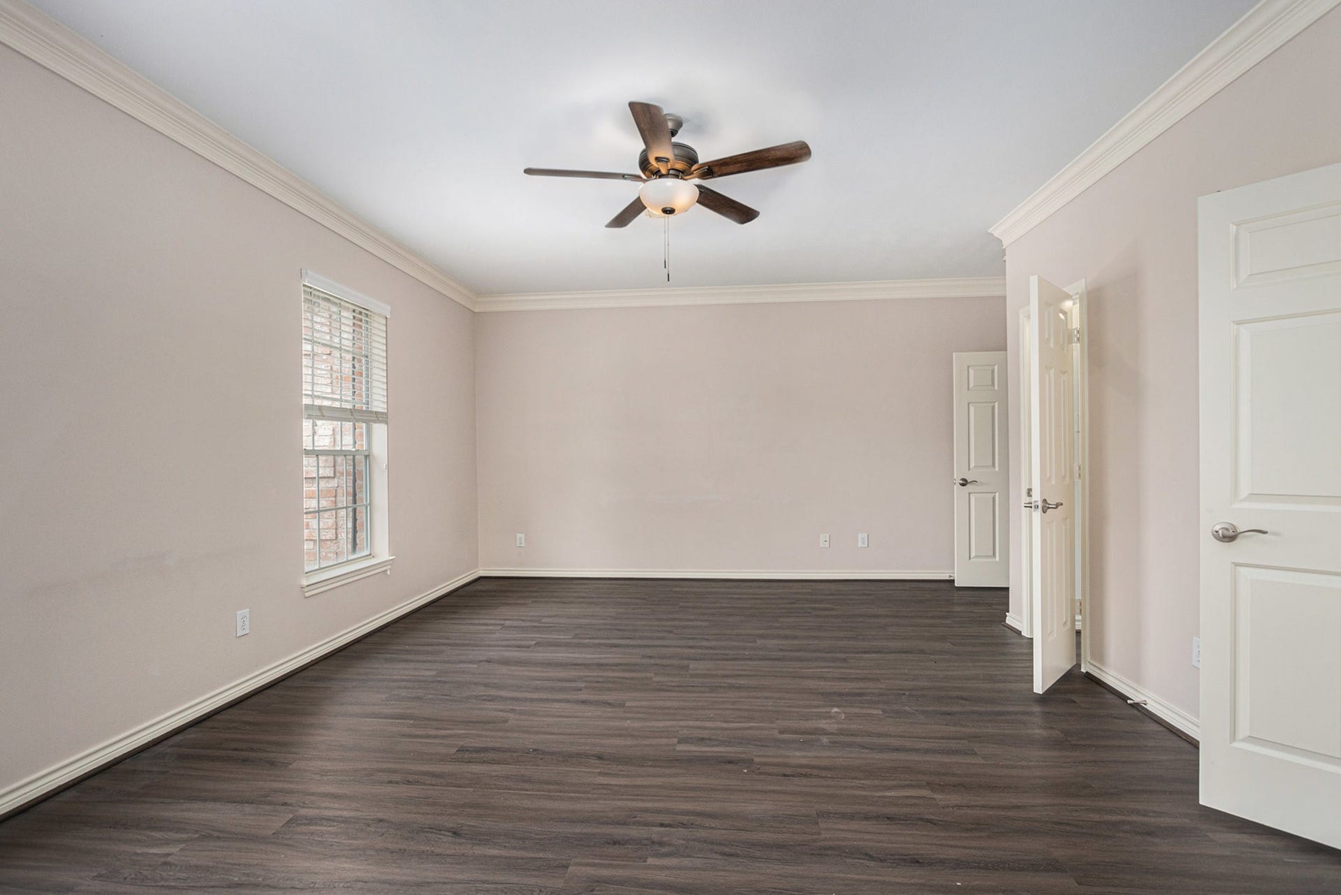 5001 Jackson Street, Houston, TX 77004 This spacious room features neutral walls, dark wood flooring, a ceiling fan, and ample natural light from a large window, creating a bright and inviting atmosphere.