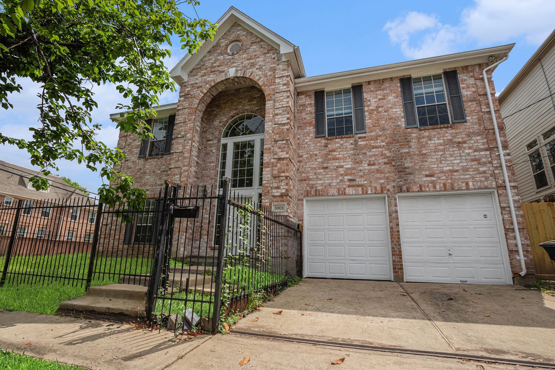 5001 Jackson Street, Houston, TX 77004 Two-story brick home with an elegant arched entrance and large windows. Features a double garage and a fenced front yard, offering both security and charm.