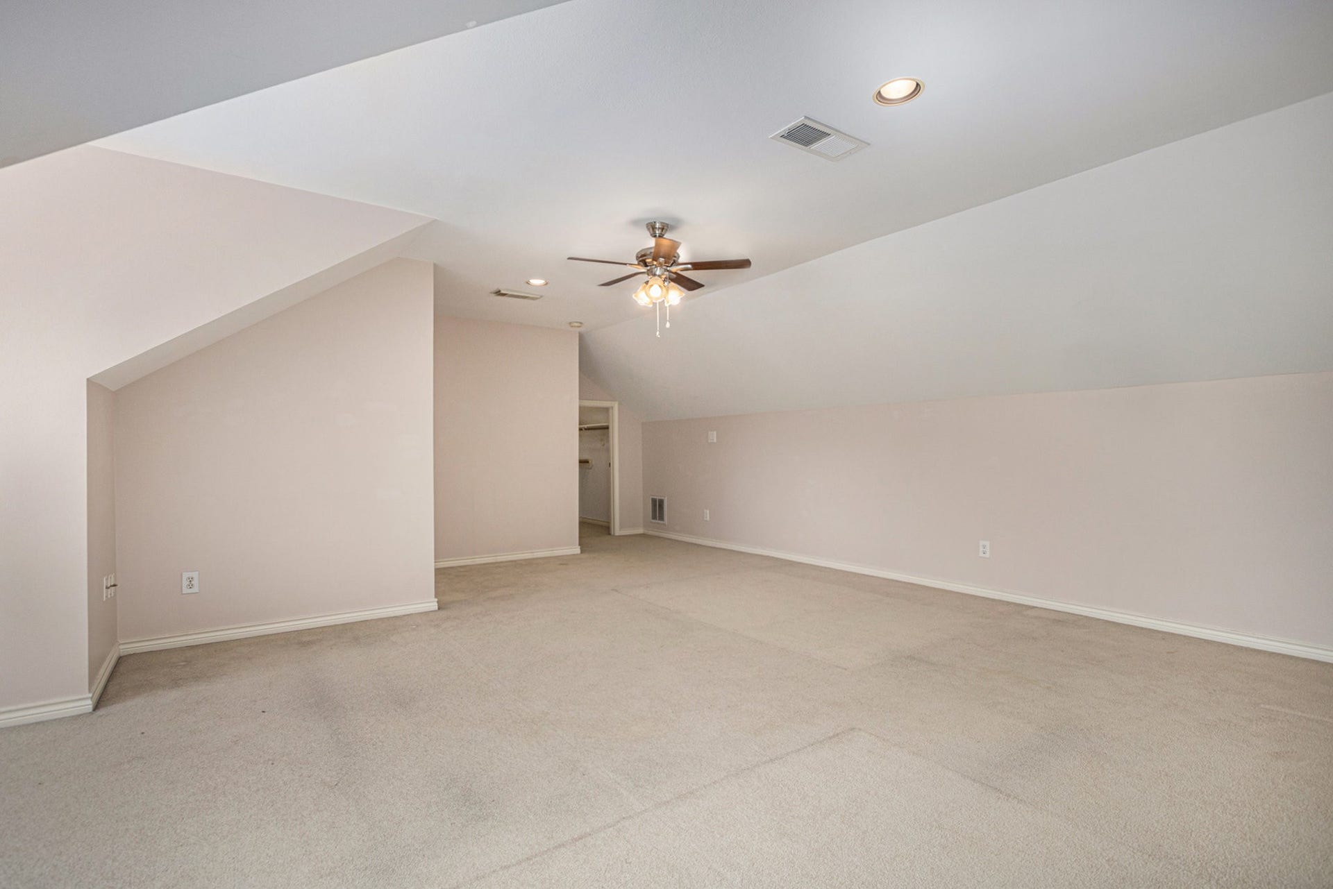 5001 Jackson Street, Houston, TX 77004 This spacious, neutral-toned attic room features a sloped ceiling, recessed lighting, and a ceiling fan, making it versatile for various uses.