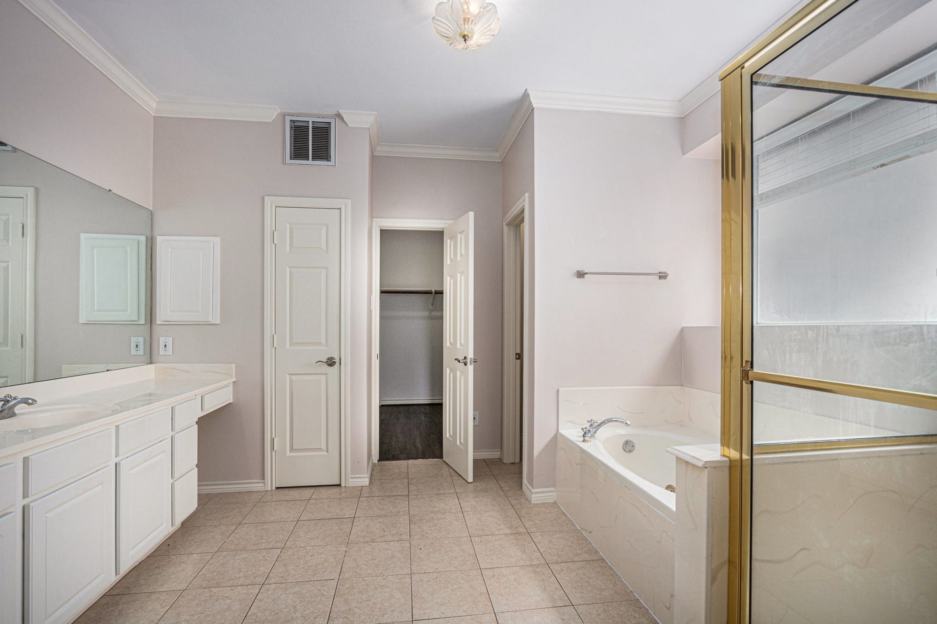 5001 Jackson Street, Houston, TX 77004 This bathroom features a spacious layout with a large vanity, a soaking tub, and a separate shower. It has neutral tile flooring and ample natural light, creating a bright and inviting space.