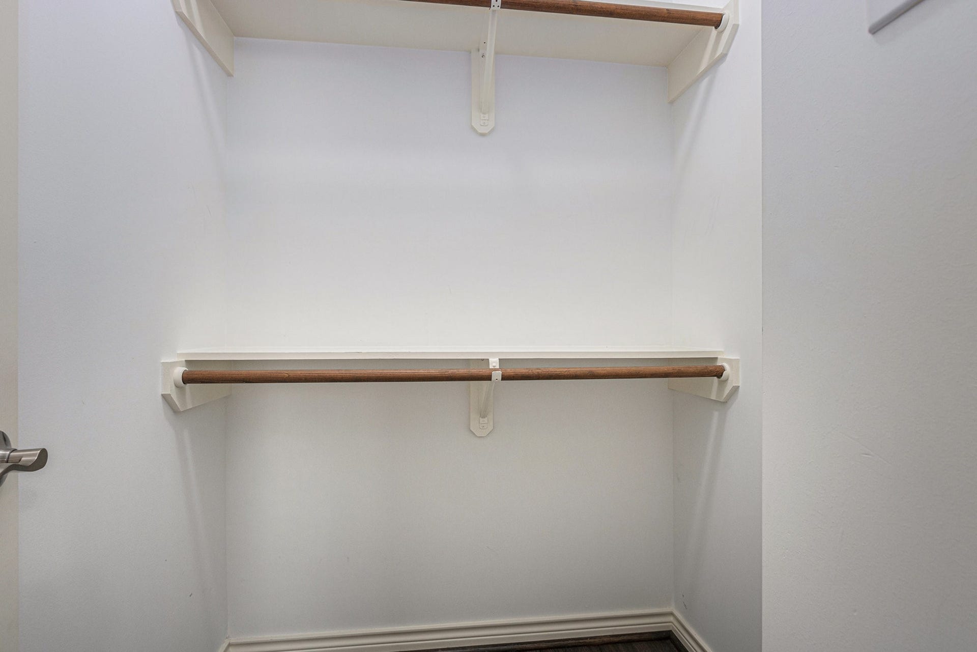 5001 Jackson Street, Houston, TX 77004 This photo shows a walk-in closet with two wooden hanging rods and white shelves, offering efficient storage space.