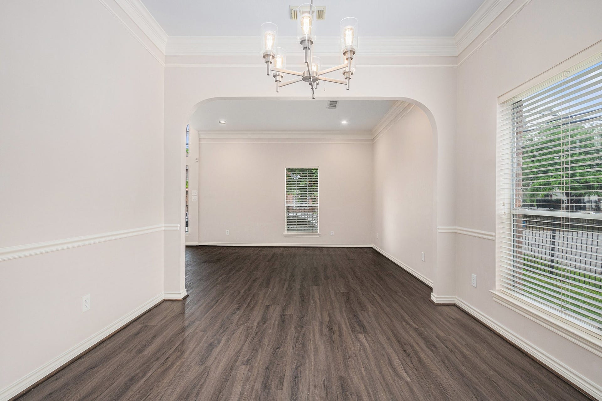 5001 Jackson Street, Houston, TX 77004 Bright, spacious room with elegant wood flooring, large windows for natural light, and a modern chandelier. Ideal for dining or living space.