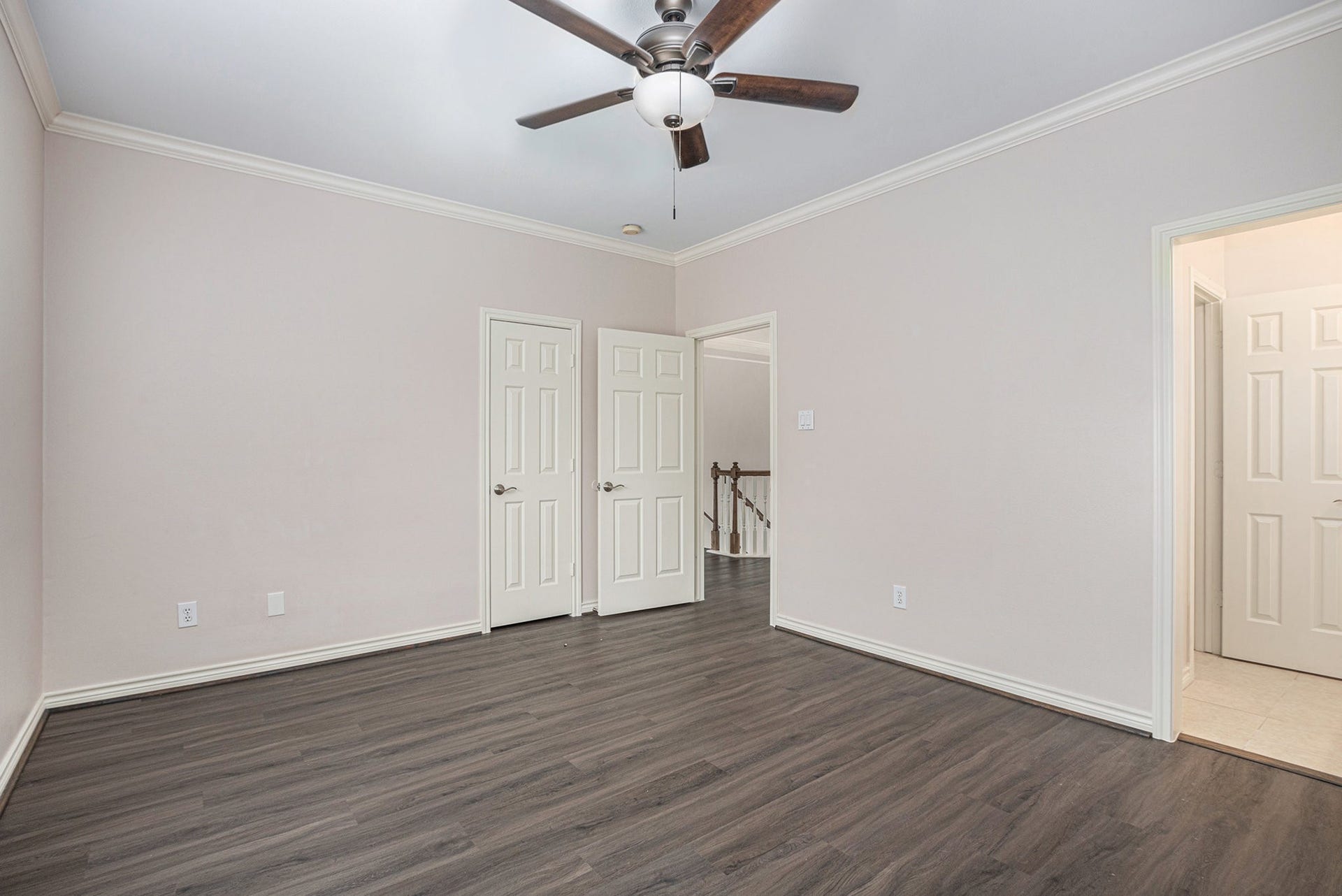 5001 Jackson Street, Houston, TX 77004 This room features sleek dark wood flooring, neutral walls, and a ceiling fan. It includes multiple doors leading to other areas, offering good connectivity within the home.