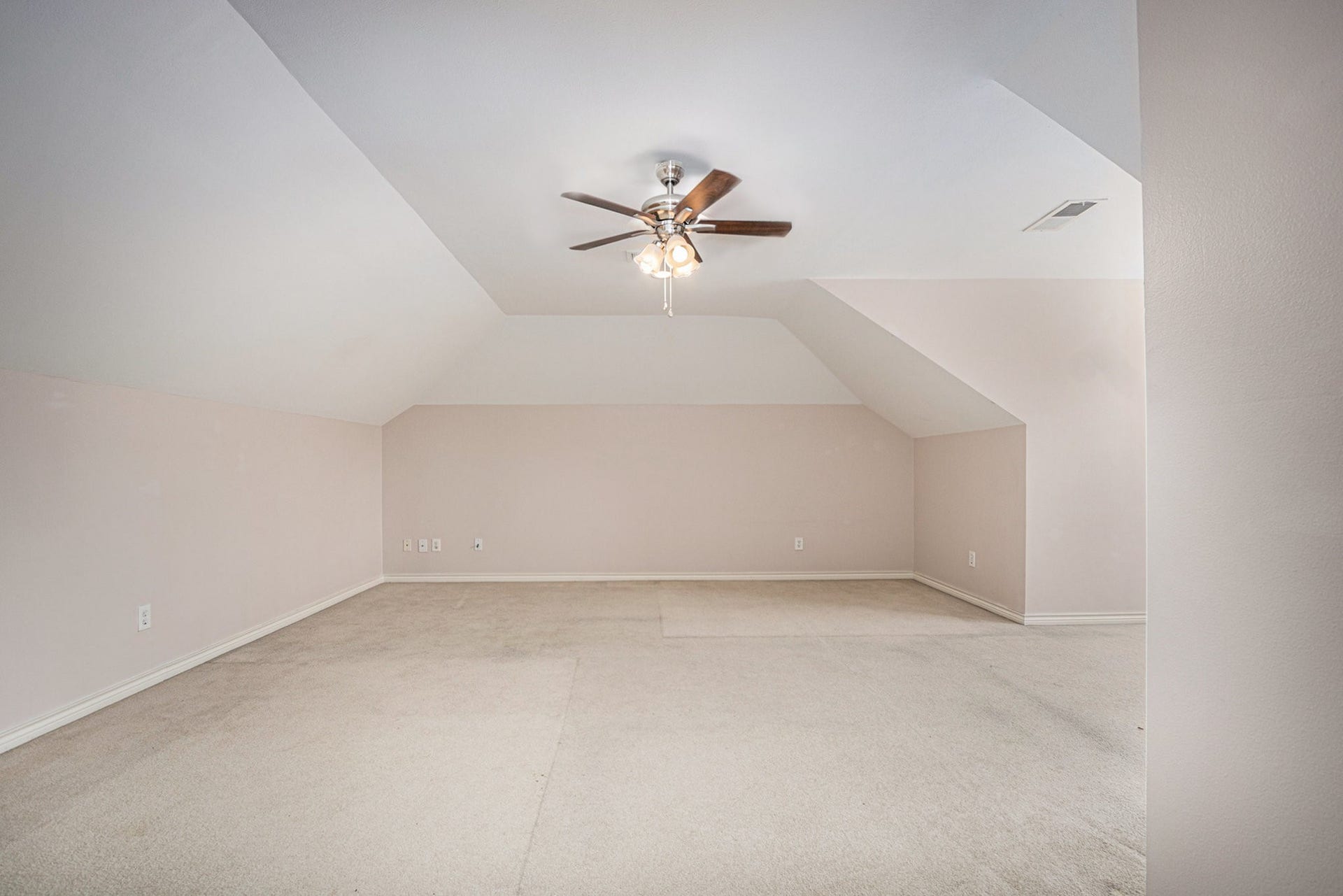 5001 Jackson Street, Houston, TX 77004 This spacious room features light-colored walls, a sloped ceiling, and a ceiling fan with lights, offering a versatile area for customization.