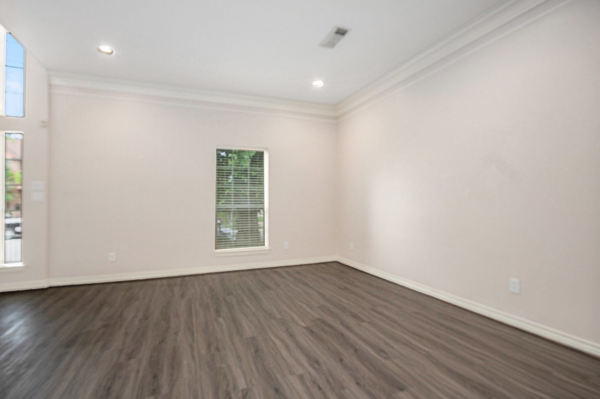 5001 Jackson Street, Houston, TX 77004 This room features neutral walls, a single window with blinds, recessed lighting, and dark wood flooring, creating a bright and modern space.
