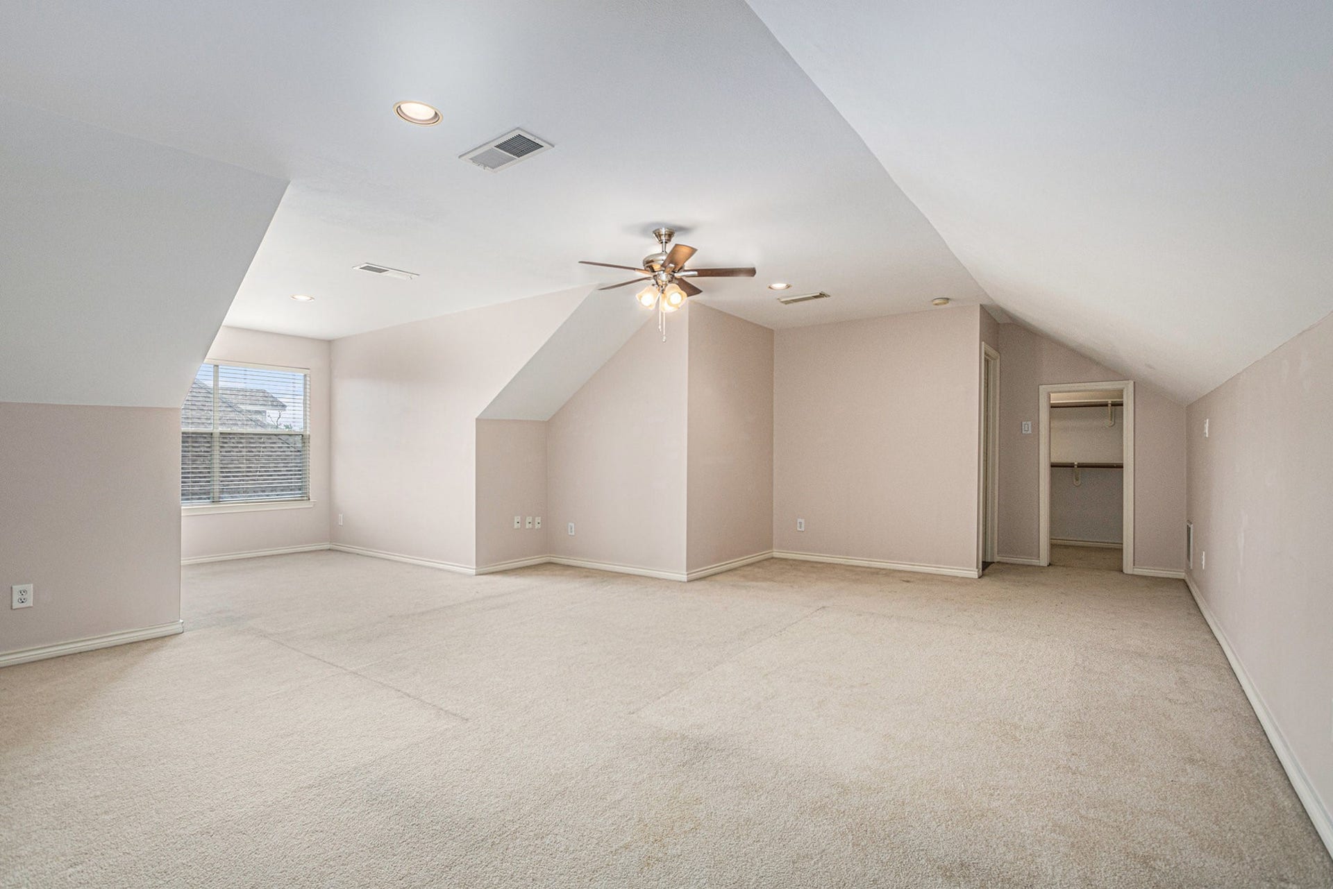 5001 Jackson Street, Houston, TX 77004 This spacious room features neutral carpeting, sloped ceilings, recessed lighting, and a ceiling fan. It includes a window for natural light and a walk-in closet, making it versatile for various uses.
