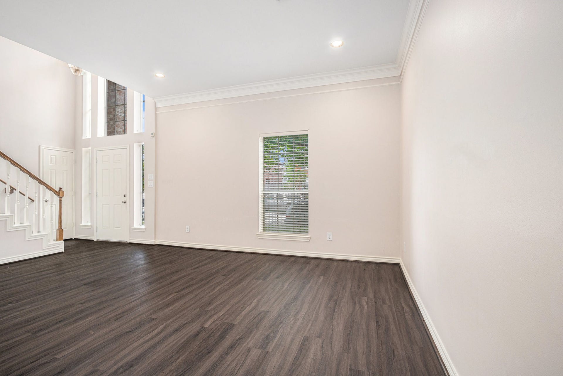 5001 Jackson Street, Houston, TX 77004 This photo showcases a bright, open living space with high ceilings and large windows. It features dark wood flooring, neutral walls, and an elegant staircase, creating a welcoming and airy atmosphere.