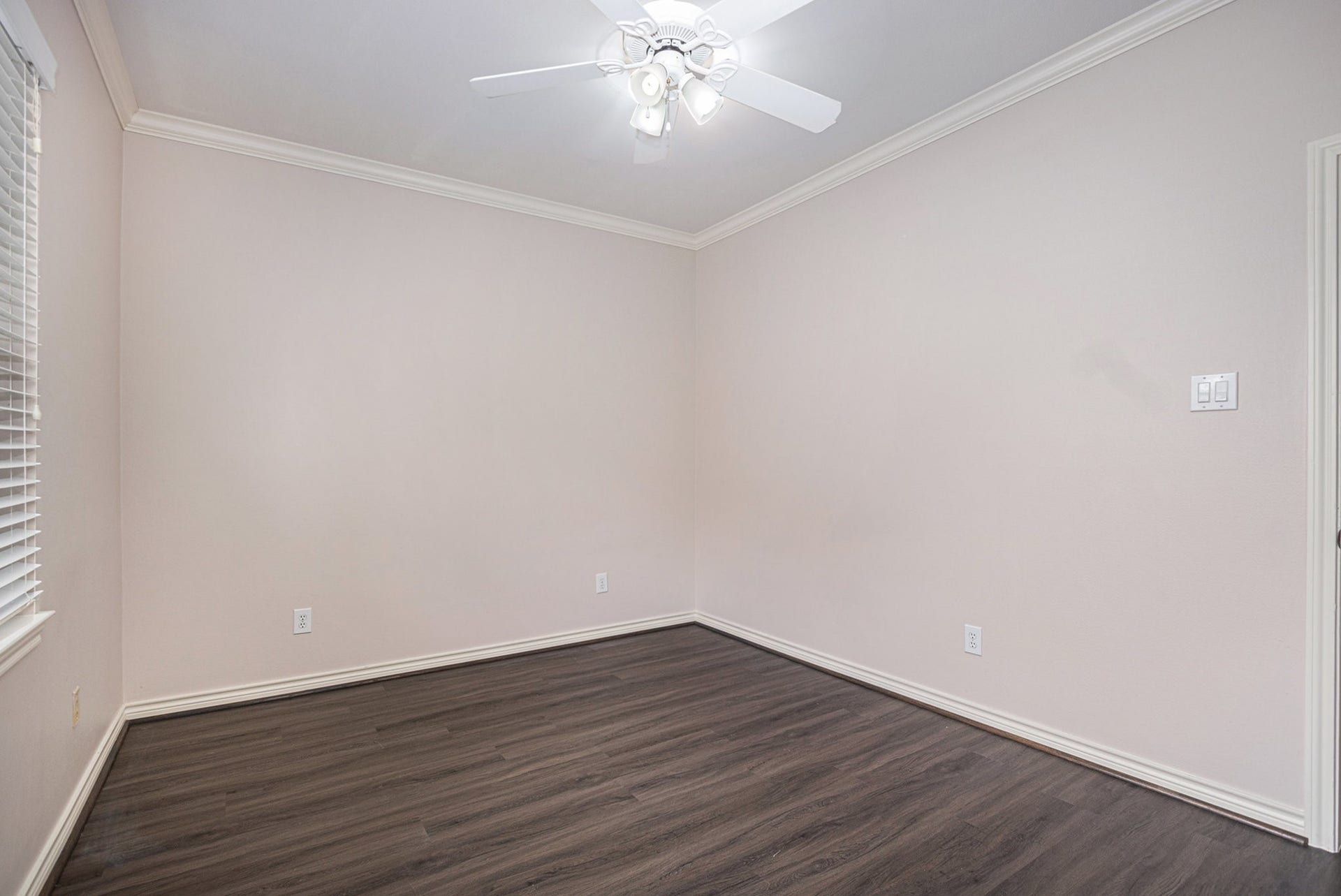 5001 Jackson Street, Houston, TX 77004 This room features neutral walls, dark wood flooring, a ceiling fan with lights, and a window with blinds, offering a bright and versatile space.