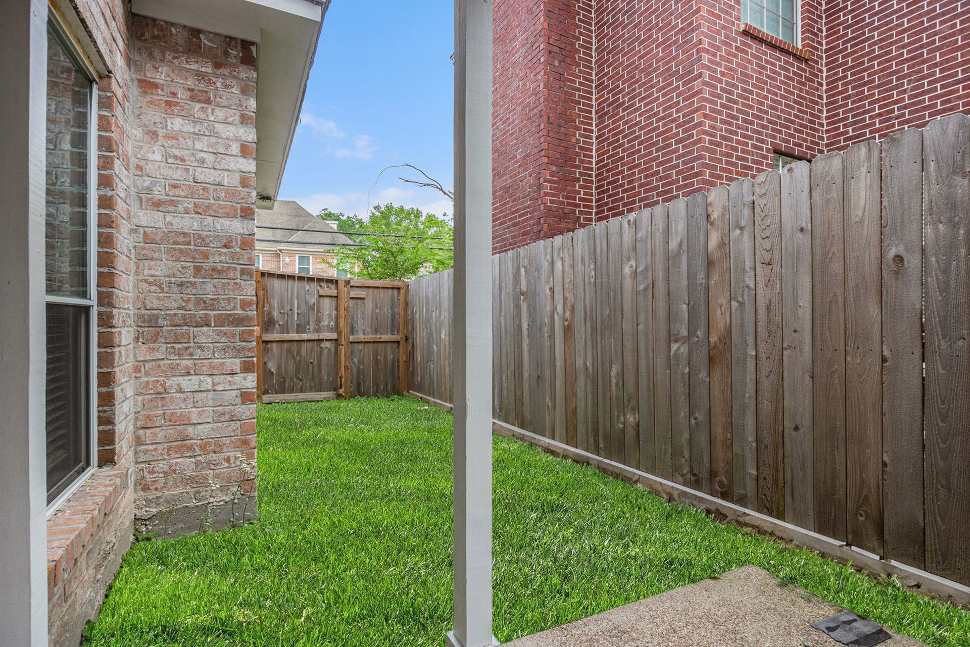 5001 Jackson Street, Houston, TX 77004 This photo shows a small, fenced backyard with a well-maintained grassy area. It features a brick exterior wall of the house and a wooden fence providing privacy. Ideal for a cozy outdoor space.