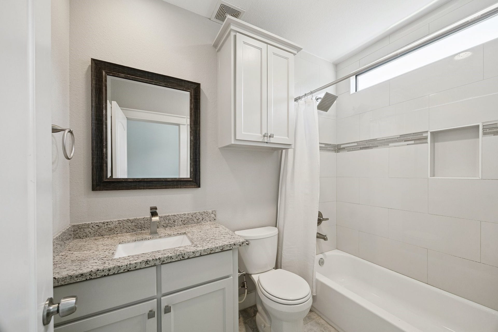 608 W 28th Street, #B, Houston, TX 77008 This lovely in-suite bath boasts granite counters with porcelain under mounted sink, stain grade cabinetry, handsome framed beveled mirror, brushed nickel fixtures and hardware, with a spacious tub shower combo with window light, rain shower head and artful built-in shower caddy nook! NICE!