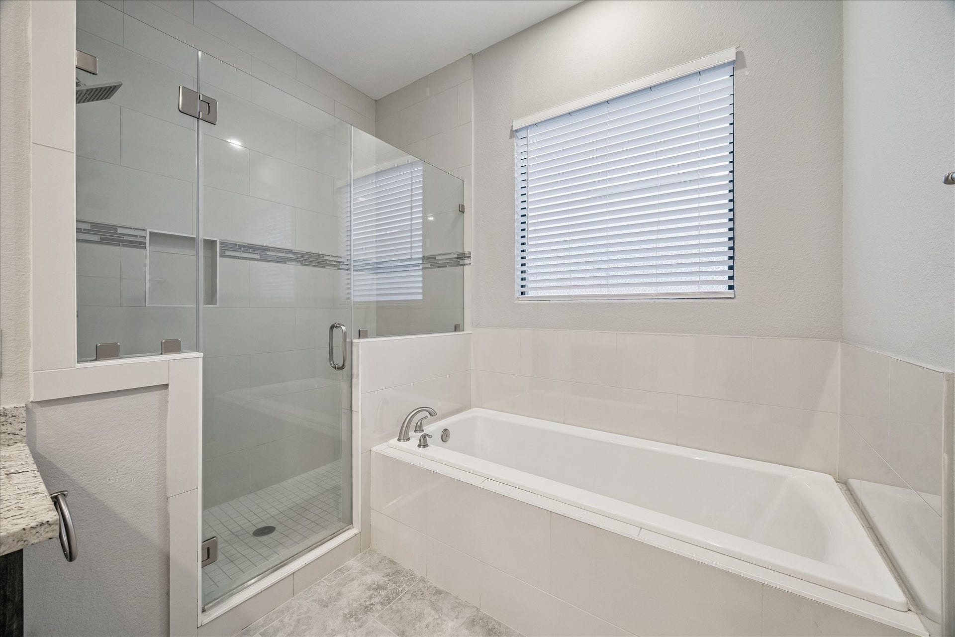 608 W 28th Street, #B, Houston, TX 77008 Close up view of the stylish Primary Bath large tub and walk-in shower! Note the frameless glass mount, custom built-in accessory shelve, artful tile work with marble trim and more! LUXURY YOU DESERVE!