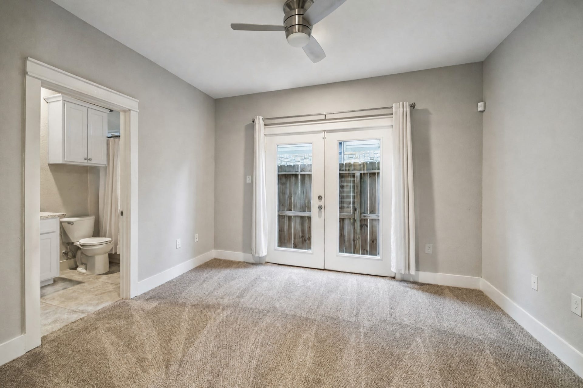 608 W 28th Street, #B, Houston, TX 77008 The downstairs Bedroom Suite boasts brand new (2026) wool carpeting, high ceilings, recessed lights and ceiling fan, 8 inch base boards, huge walk-in closet and in-suite bath. French doors with light neutral drapes open to a fenced back yard with just the right amount of outside space for pets or the little ones.