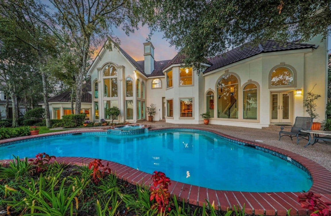 35 W Isle Place, The Woodlands, TX 77381 Resort-style backyard featuring a sparkling pool, lush landscaping, and an elegant covered patio.