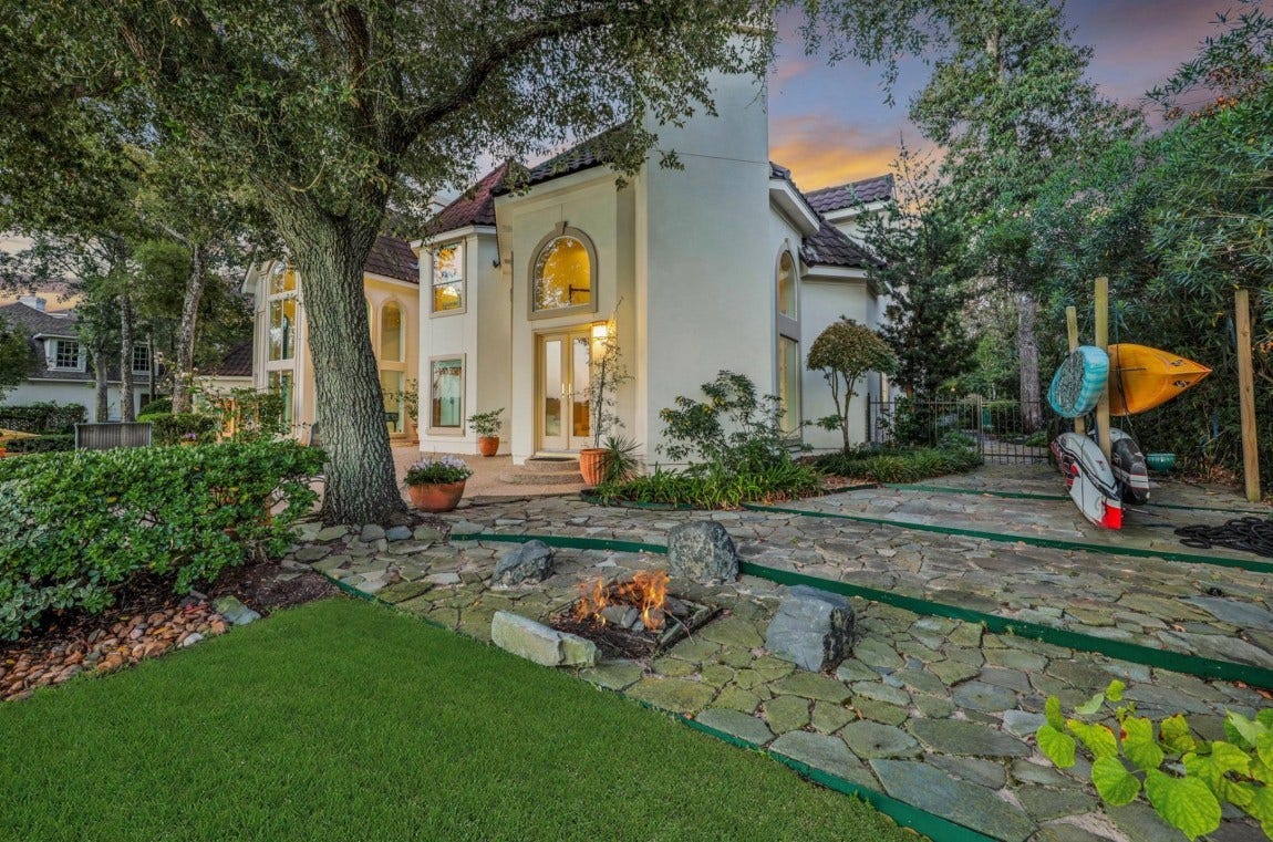 35 W Isle Place, The Woodlands, TX 77381 Beautifully landscaped backyard with mature trees, manicured lawn, and inviting outdoor living spaces.
