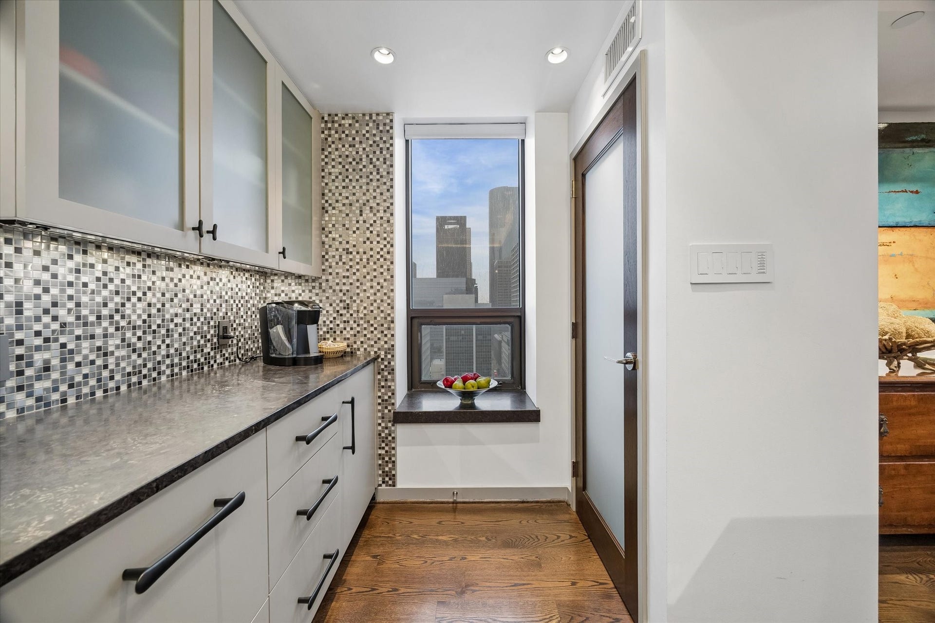 1111 Caroline Street, #2601, Houston, TX 77010 Additional kitchen counter provides a separate surface for preparation or serving. Upper cabinets and lower drawers extend storage, while a narrow window brings in daylight and a city outlook.