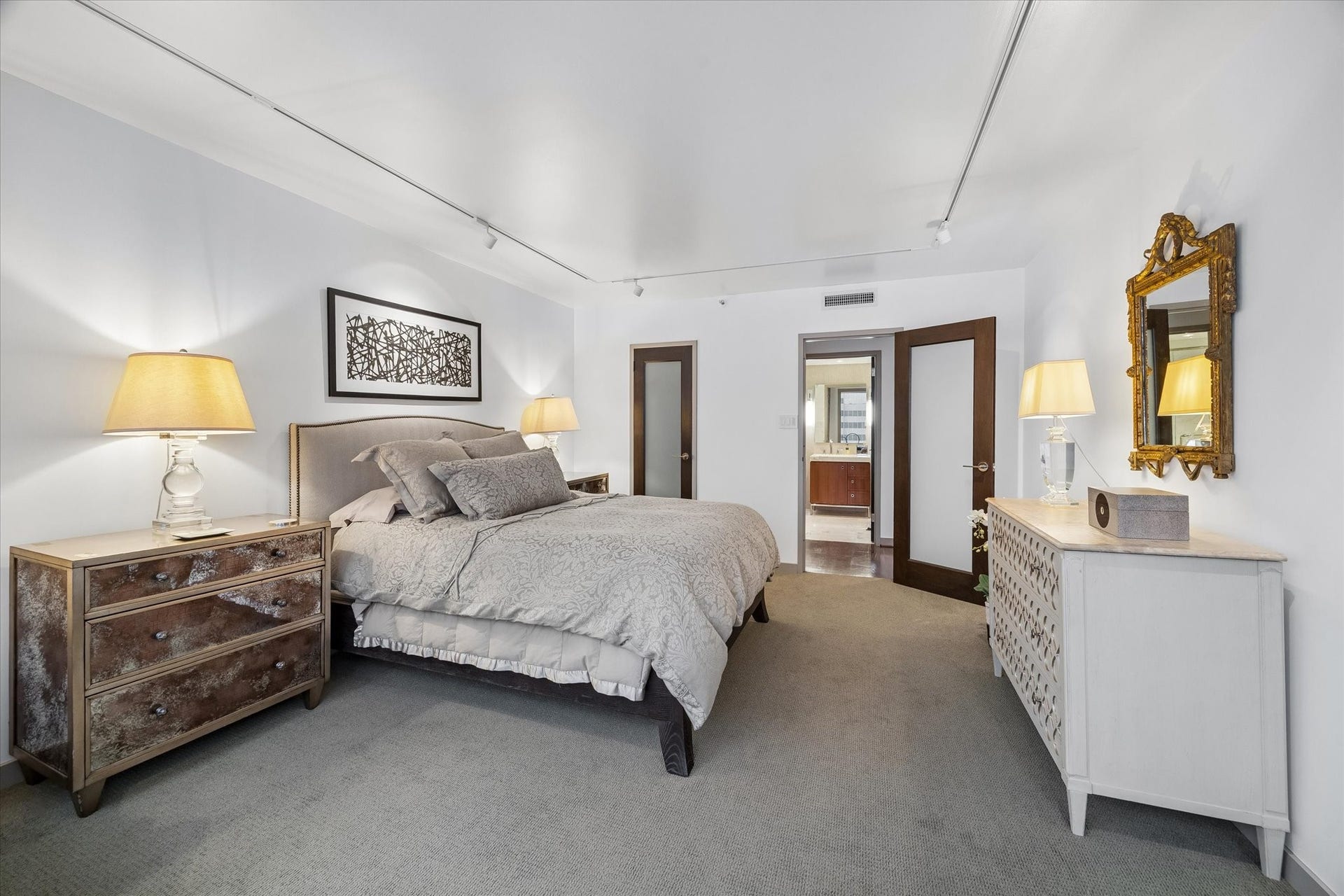 1111 Caroline Street, #2601, Houston, TX 77010 Reverse bedroom view shows the route toward the adjoining hall and bath. Frosted glass door inserts and track lighting continue the interior details found throughout the residence.