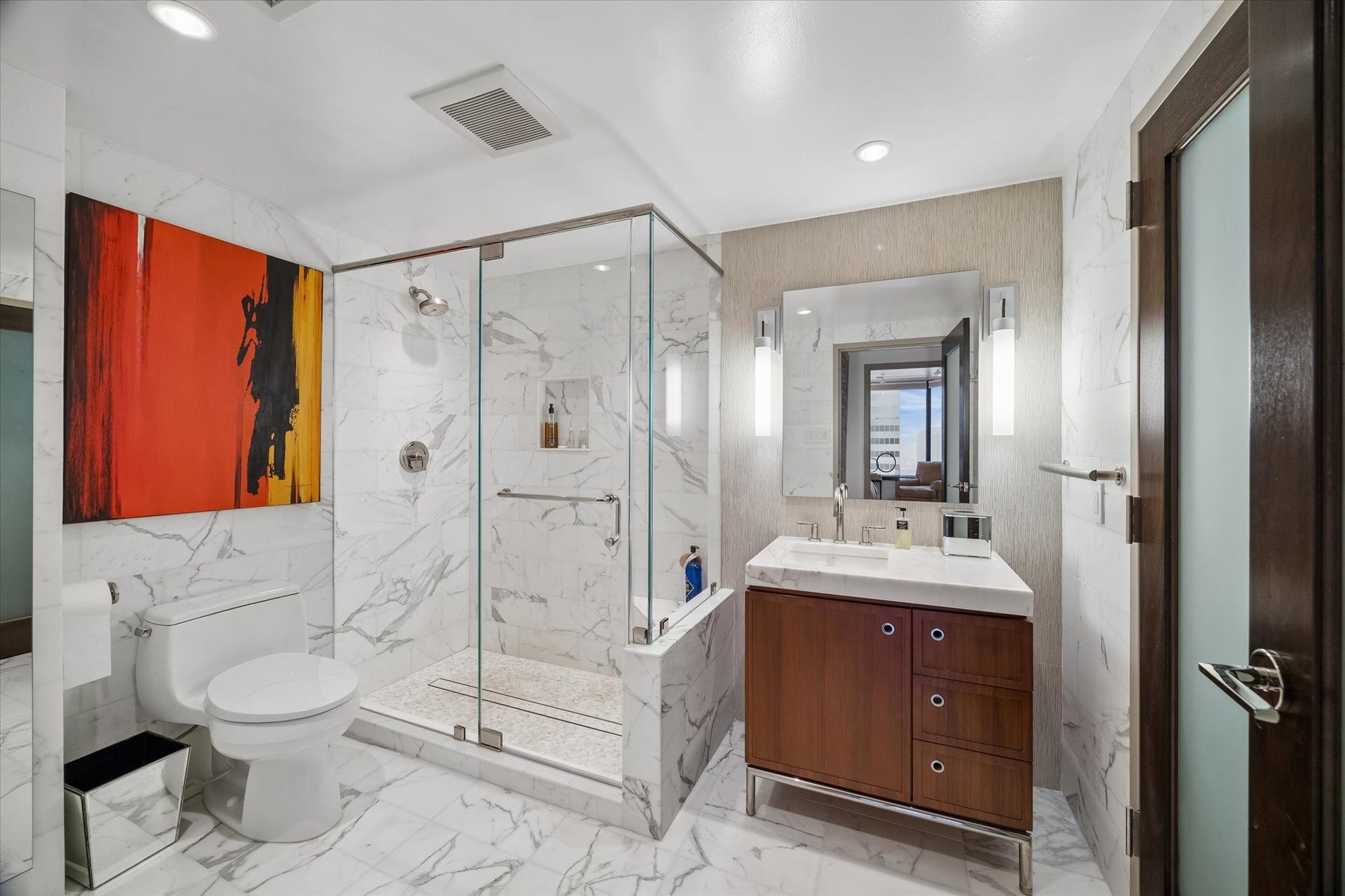 1111 Caroline Street, #2601, Houston, TX 77010 Glass enclosed shower, mosaic shower floor and veined tile define the bath. Vanity drawers and cabinets provide storage beside the sink, with vertical lighting flanking the mirror.